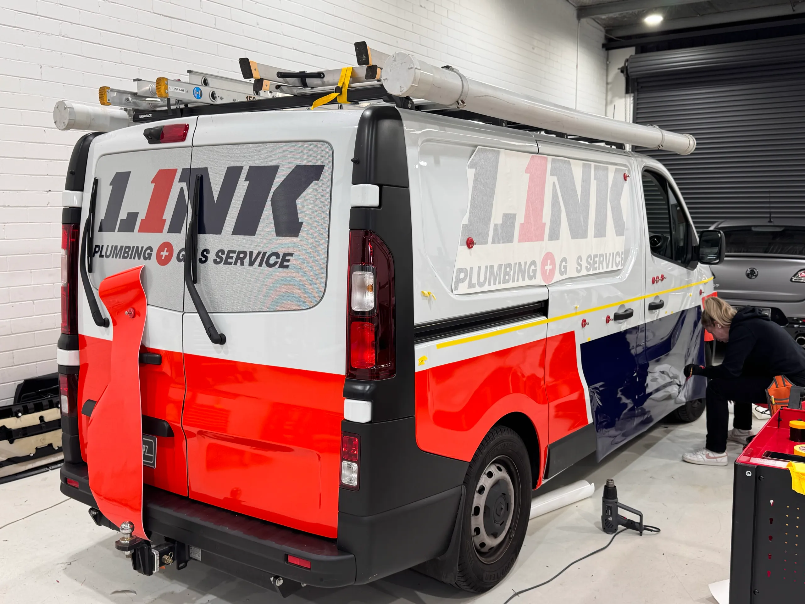 Link Plumbing van during wrapping with loose rear film and an installer at the side