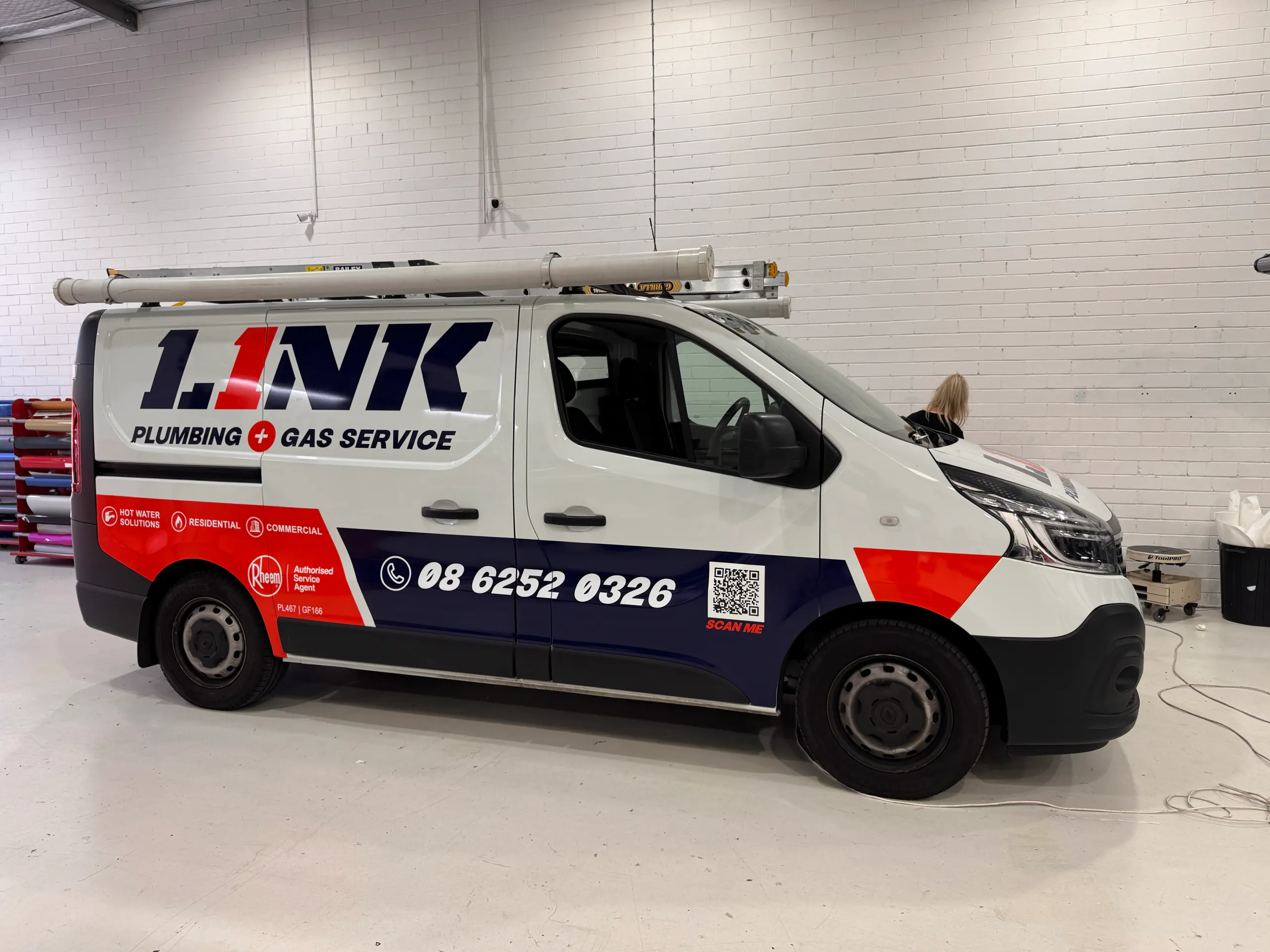 White Link Plumbing and Gas Service van with navy and orange-red graphics in the workshop