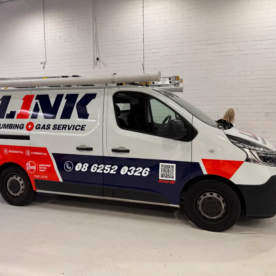 White Link Plumbing and Gas Service van with navy and orange-red graphics in the workshop