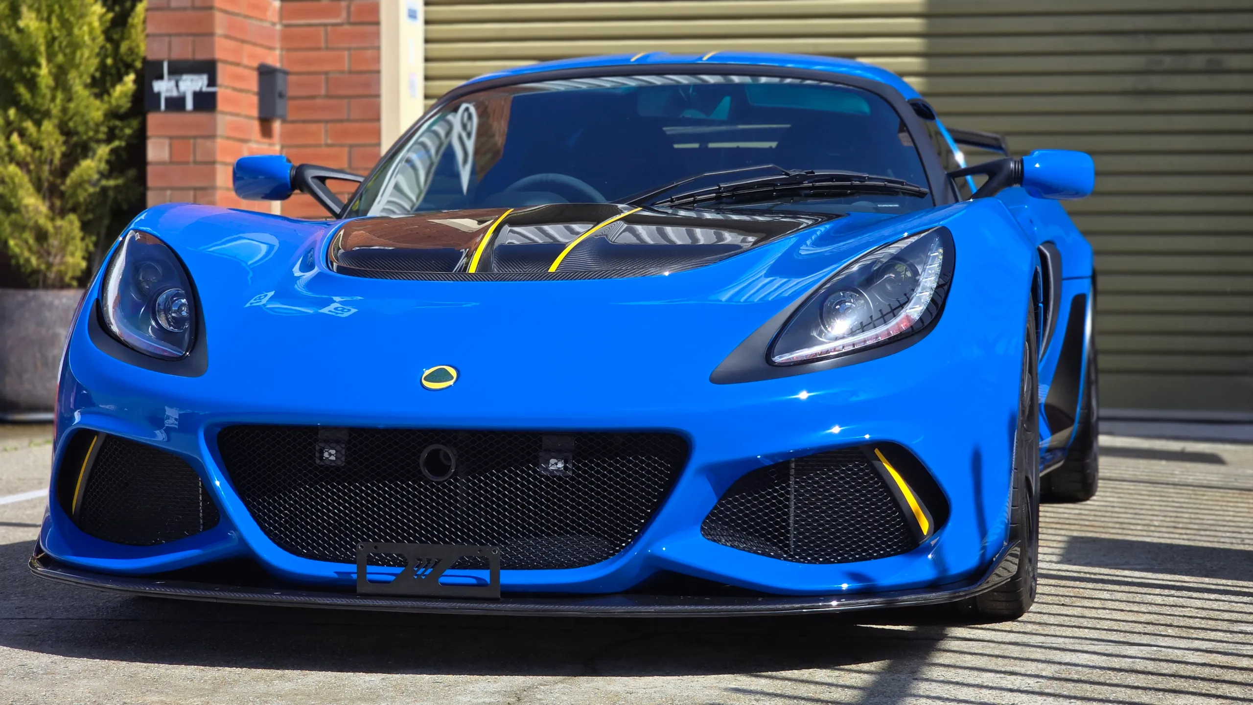 Front view of the blue Lotus Exige with yellow accents on the carbon bonnet panel
