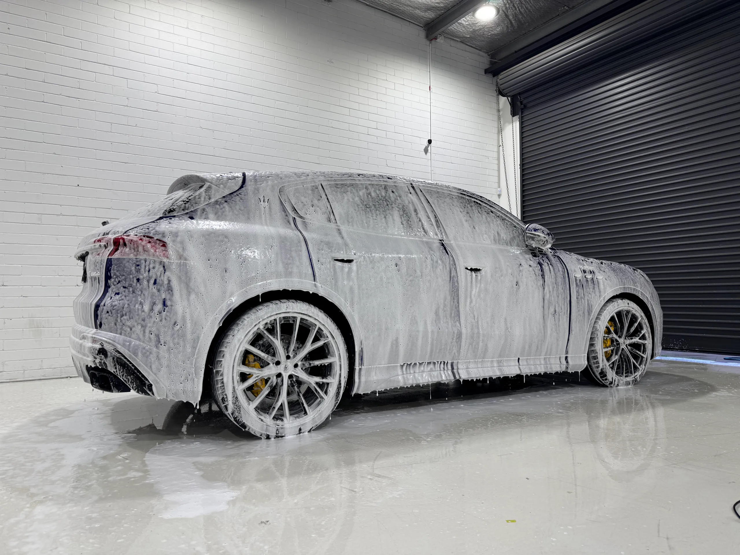 Maserati Grecale covered in wash foam inside the workshop