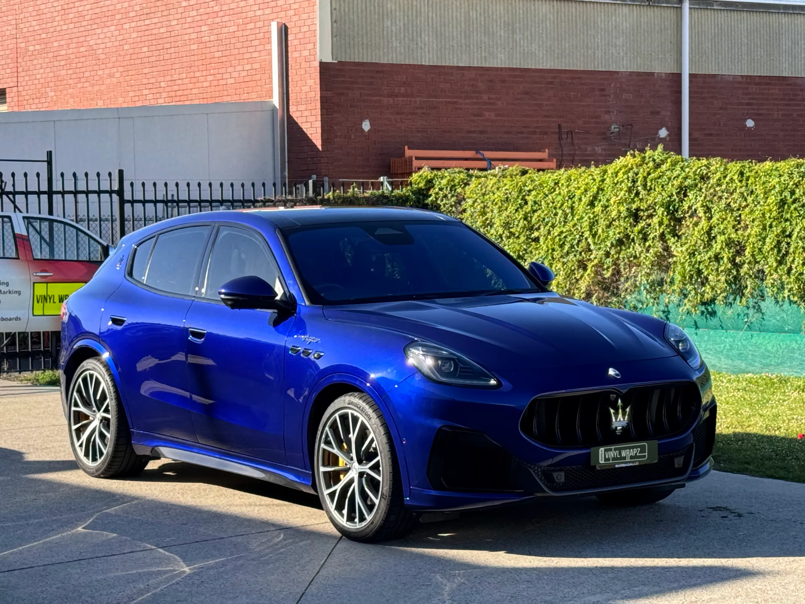 Gloss blue Maserati Grecale viewed from the front quarter outside the workshop