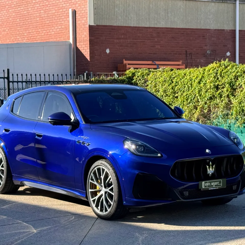 Gloss blue Maserati Grecale viewed from the front quarter outside the workshop