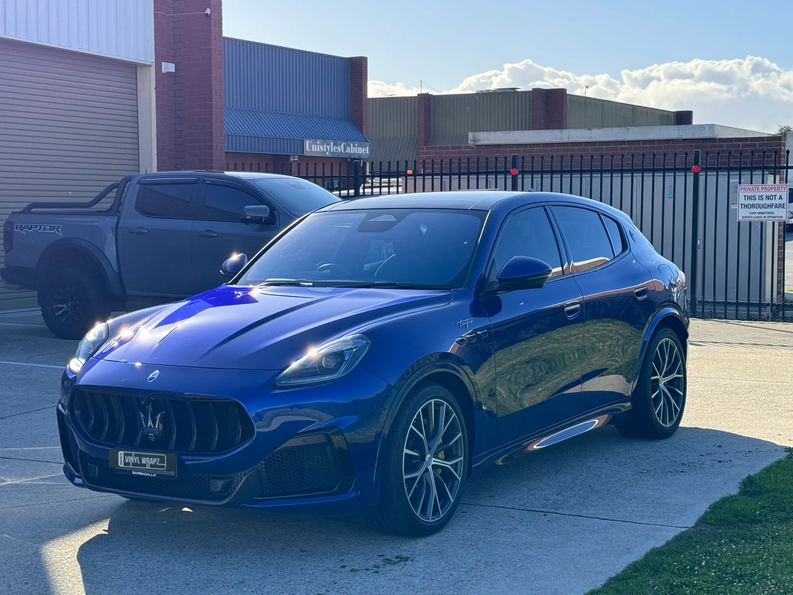 Blue Maserati Grecale front quarter reflecting sunlight outside the workshop