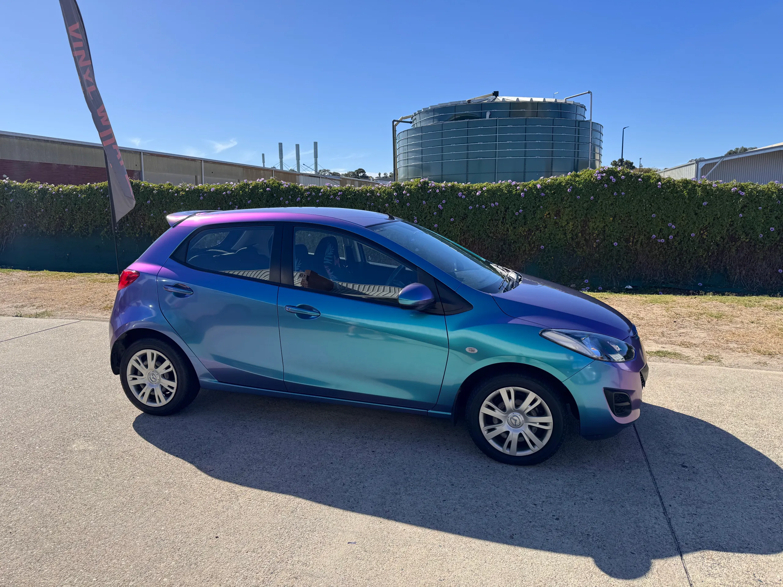 Turquoise and lavender Mazda 2 during wrapping in the workshop, side