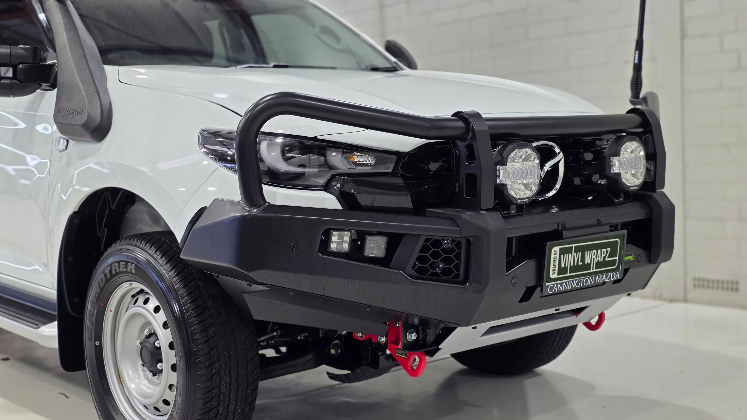 Front wheel, bullbar and driving lights on a white Mazda BT-50 in the workshop