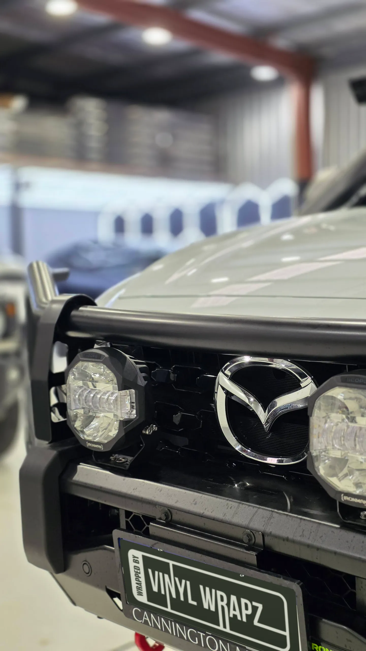 Mazda badge, bullbar and driving lights on the front of a white BT-50