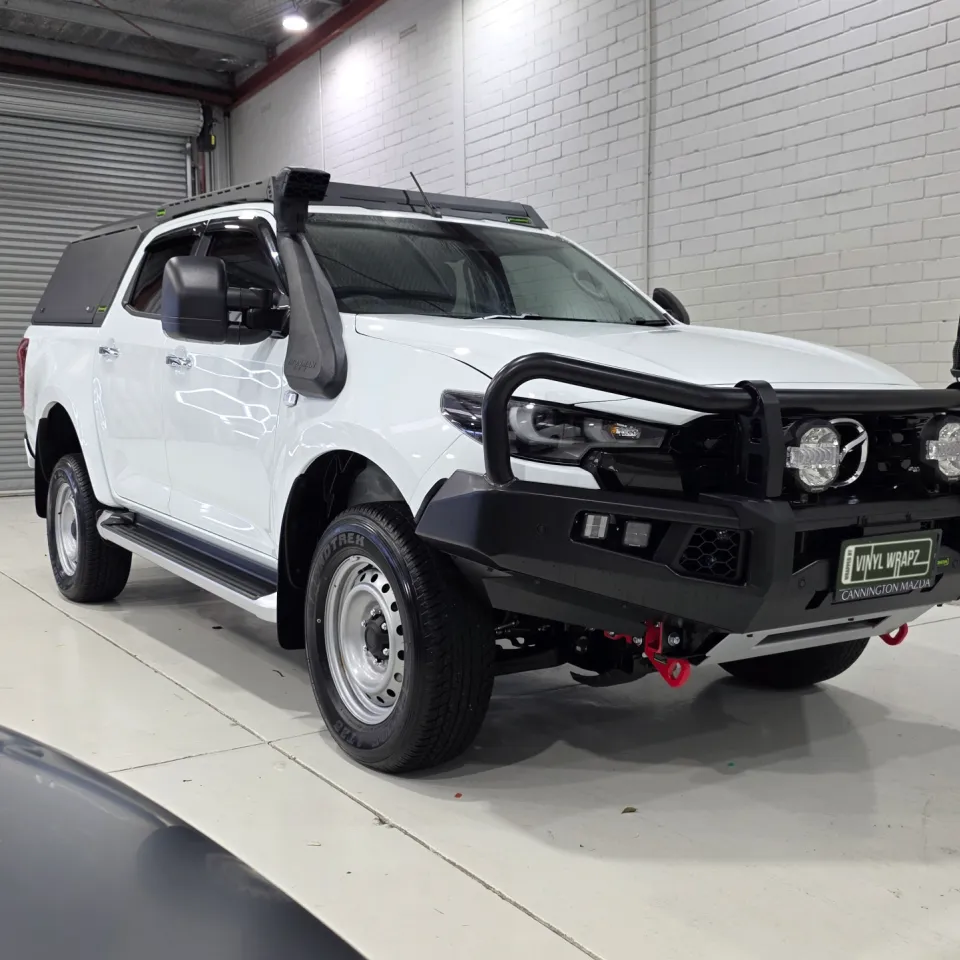 White Mazda BT-50 with a bullbar, snorkel and black canopy in the workshop