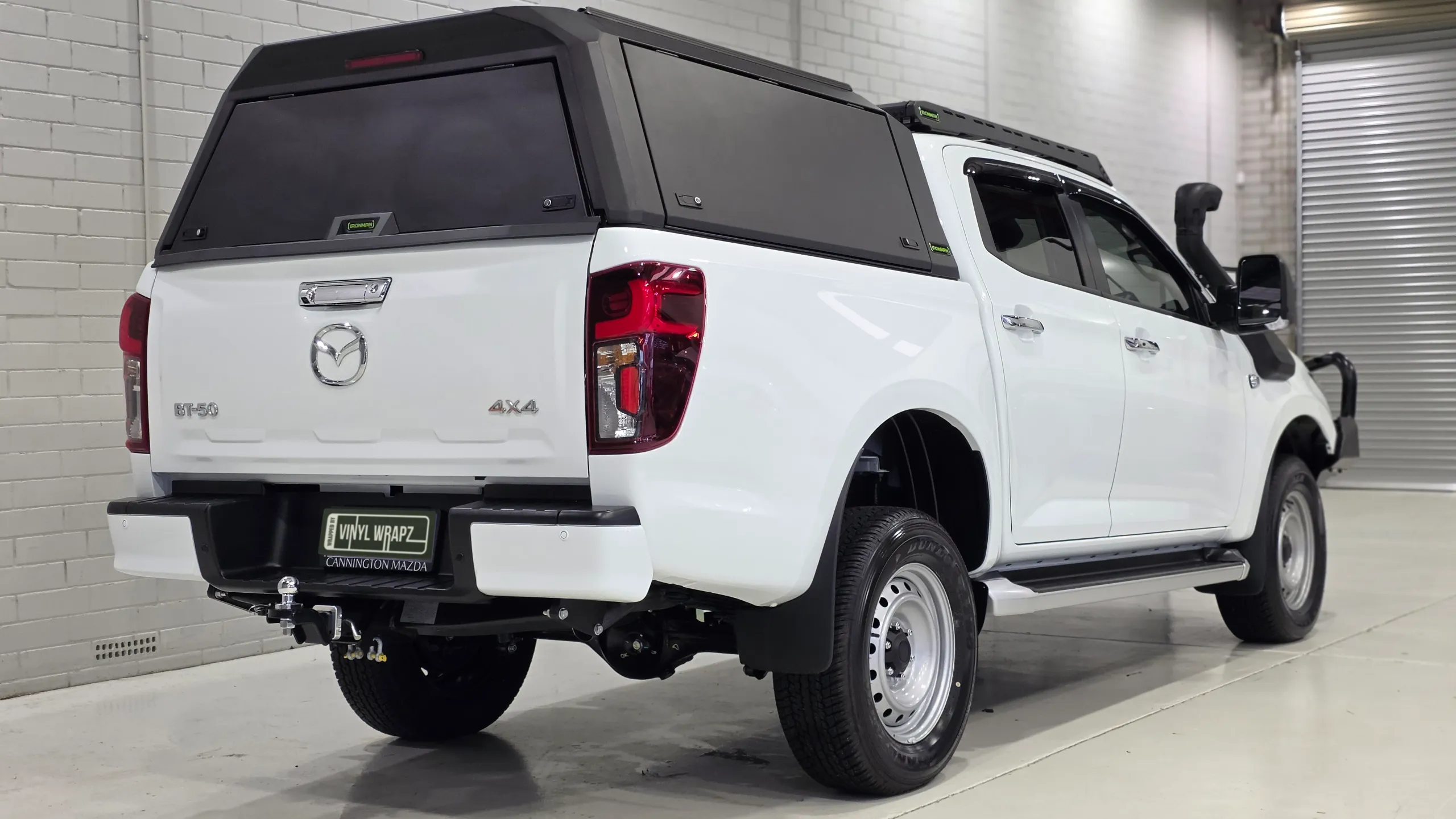 Rear-quarter view of the white Mazda BT-50 and its black canopy