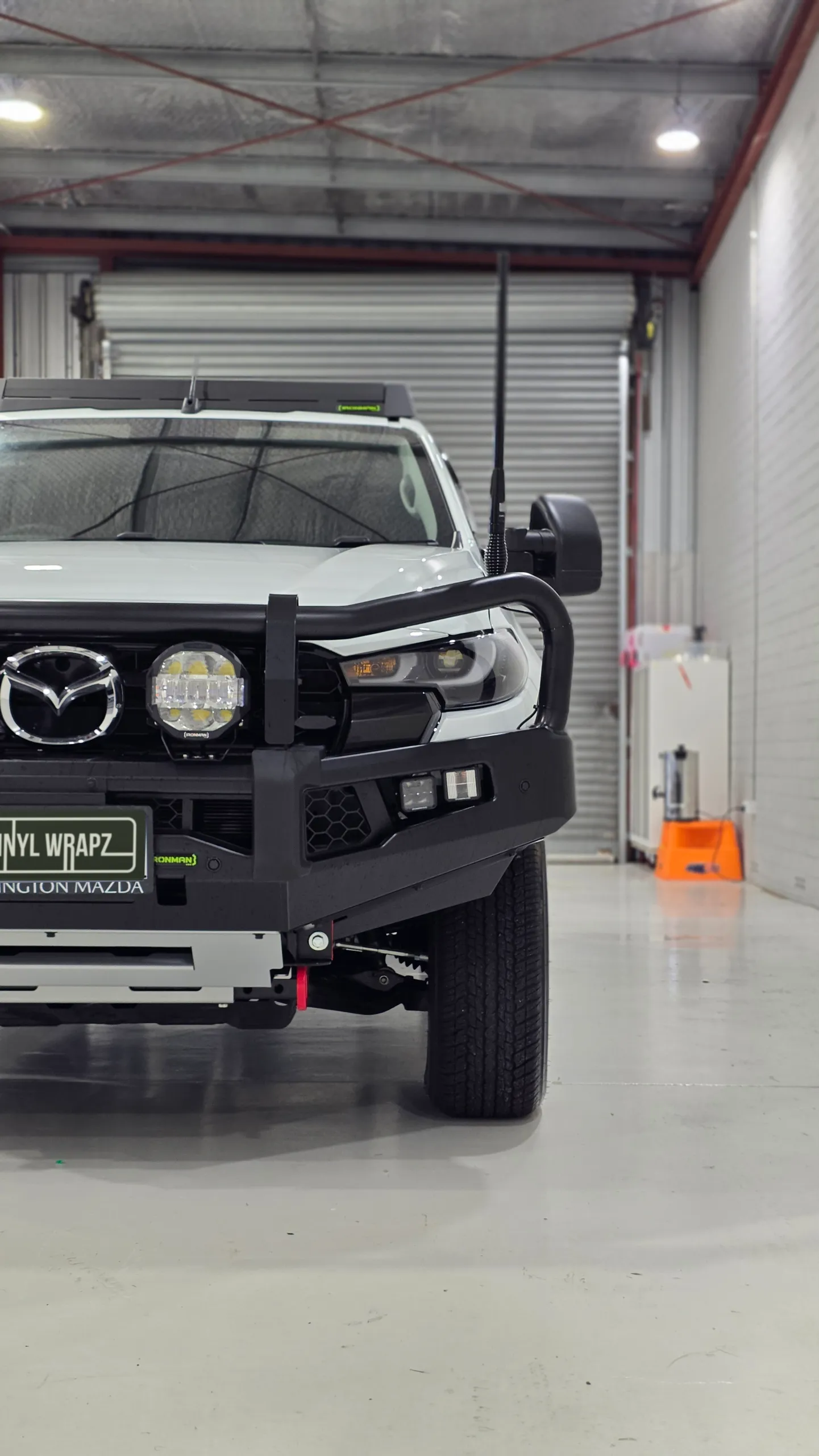 Cropped front view of the white Mazda BT-50 showing its bullbar and driving lights