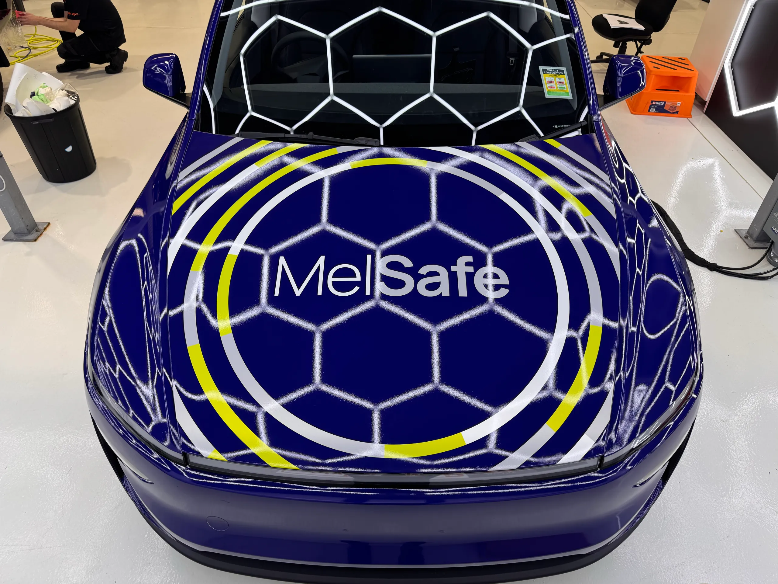 White and yellow MelSafe bonnet graphics fitted to the blue Tesla Model Y