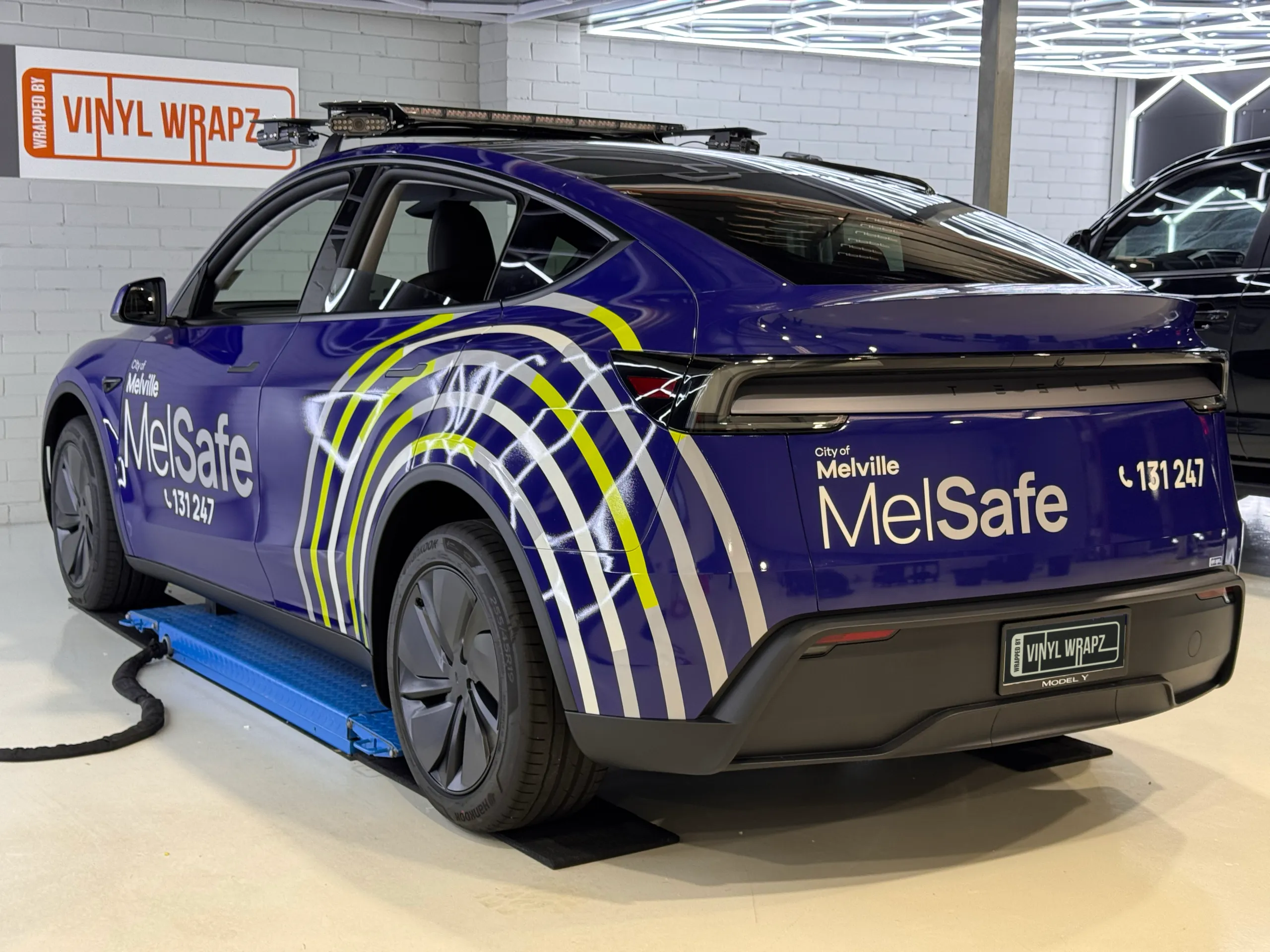 Blue City of Melville MelSafe Tesla Model Y viewed from the rear quarter in the workshop