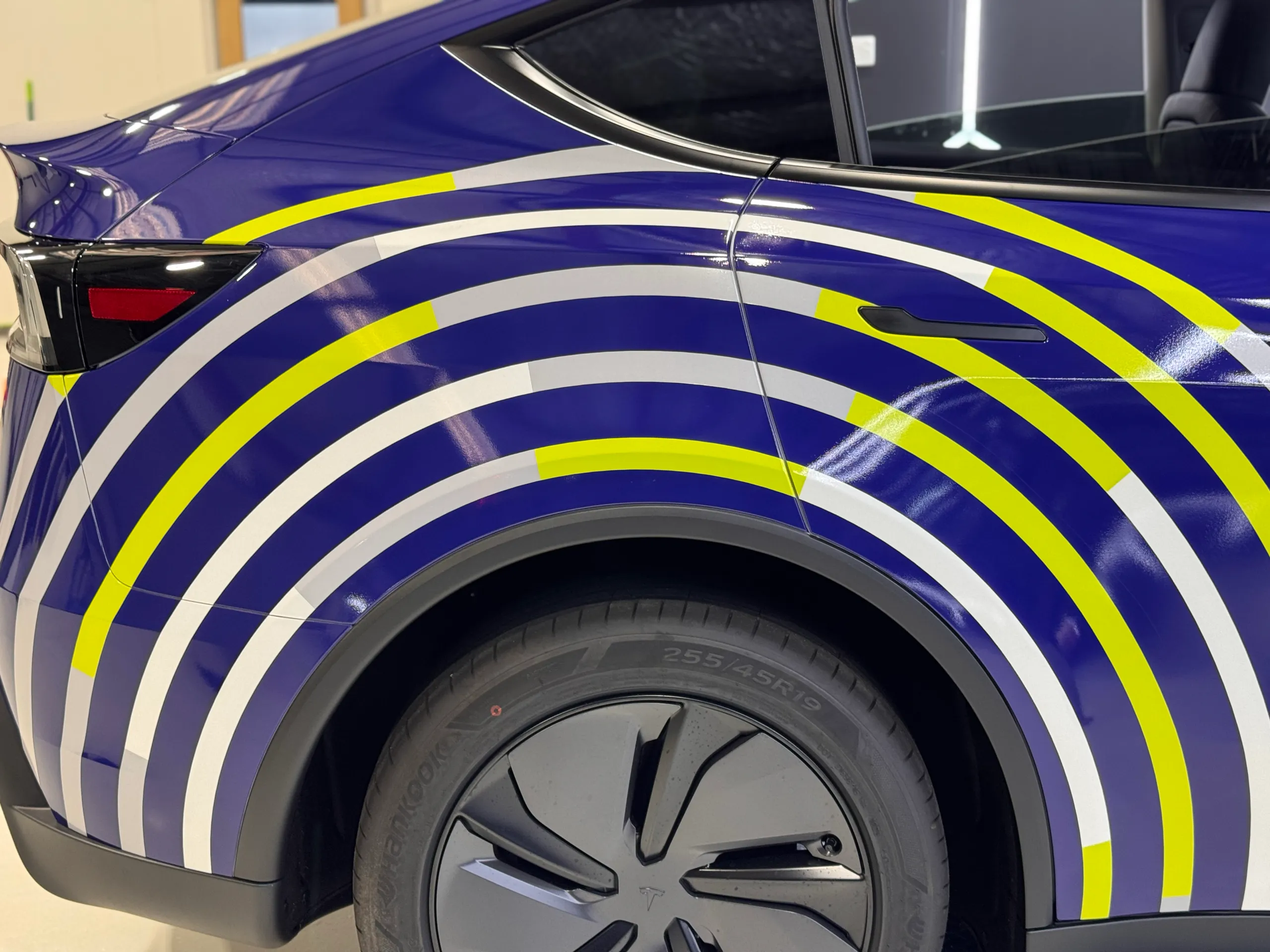 White and yellow rings across the blue Tesla rear door and wheel arch