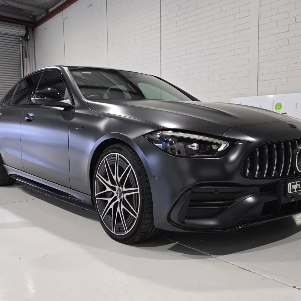 Satin dark grey Mercedes-AMG C43 viewed from the front quarter inside the workshop