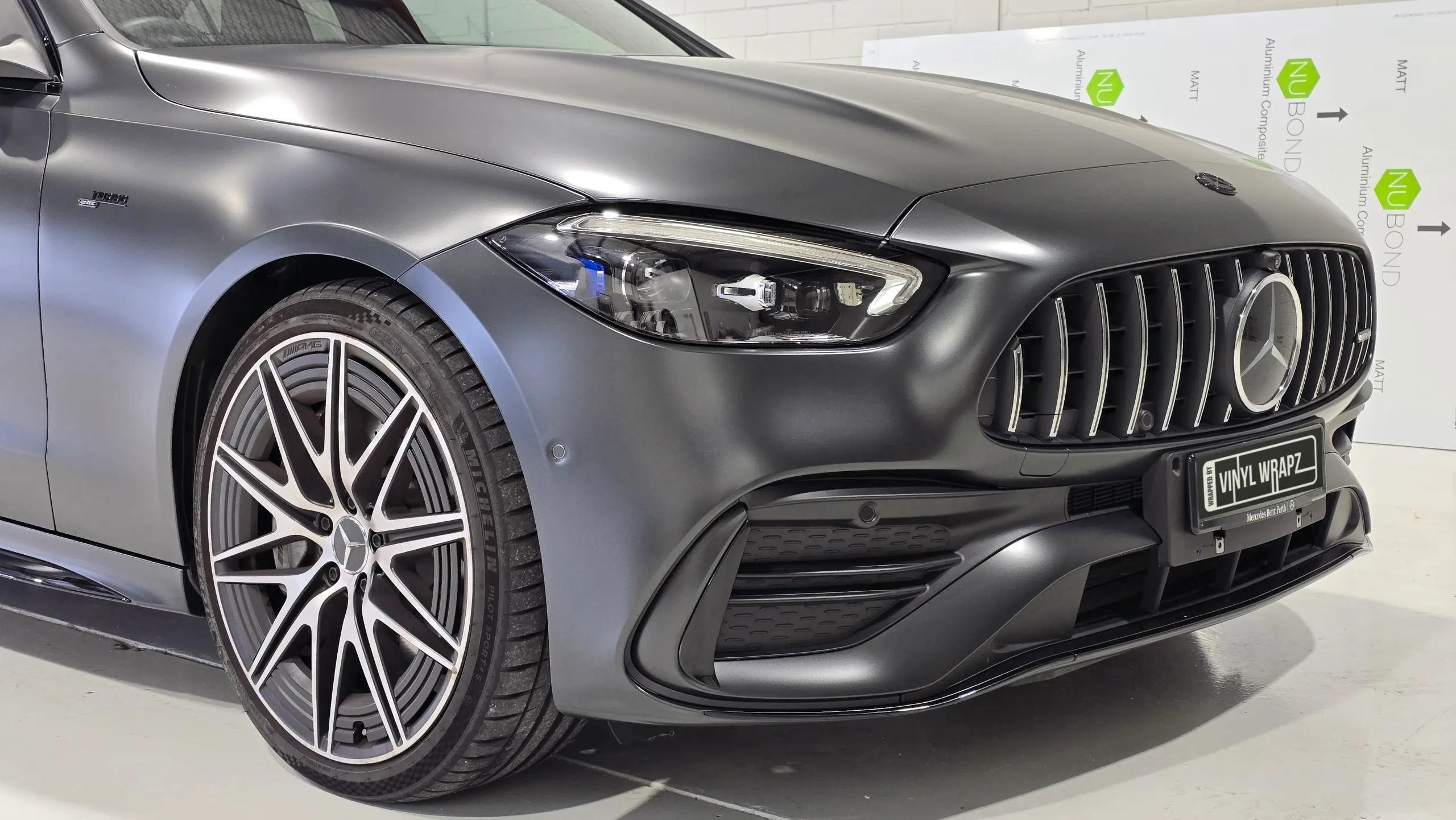 Close-up of the headlight, front wheel and satin grey bodywork on a Mercedes-AMG C43