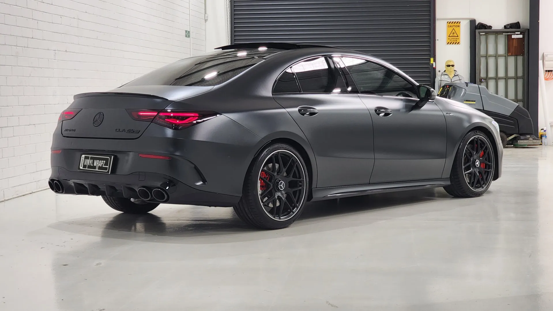 Satin dark grey Mercedes-AMG CLA 45 S viewed from the rear quarter in the workshop