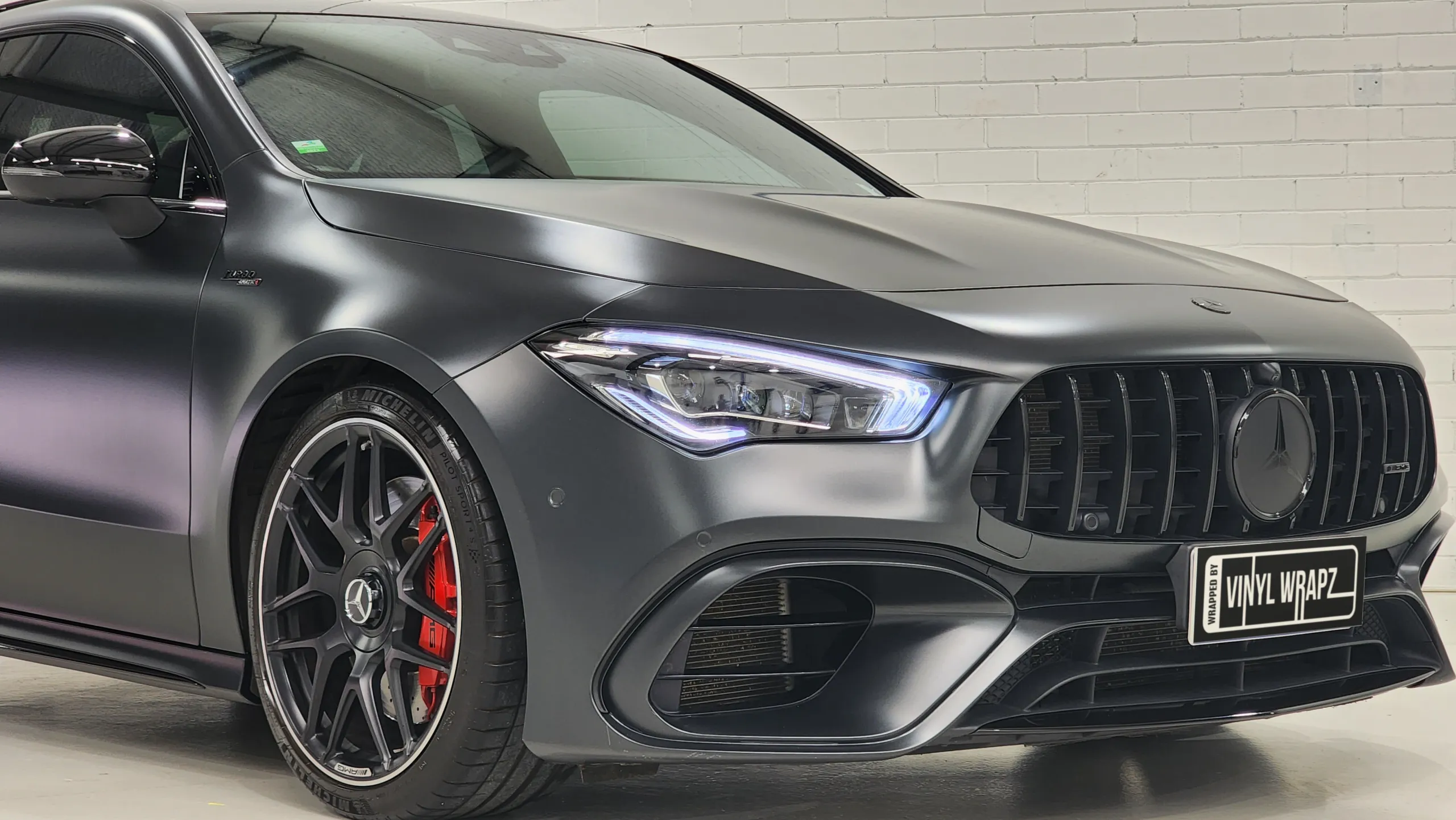 Front-quarter detail of the satin dark grey Mercedes-AMG CLA 45 S and red brake caliper
