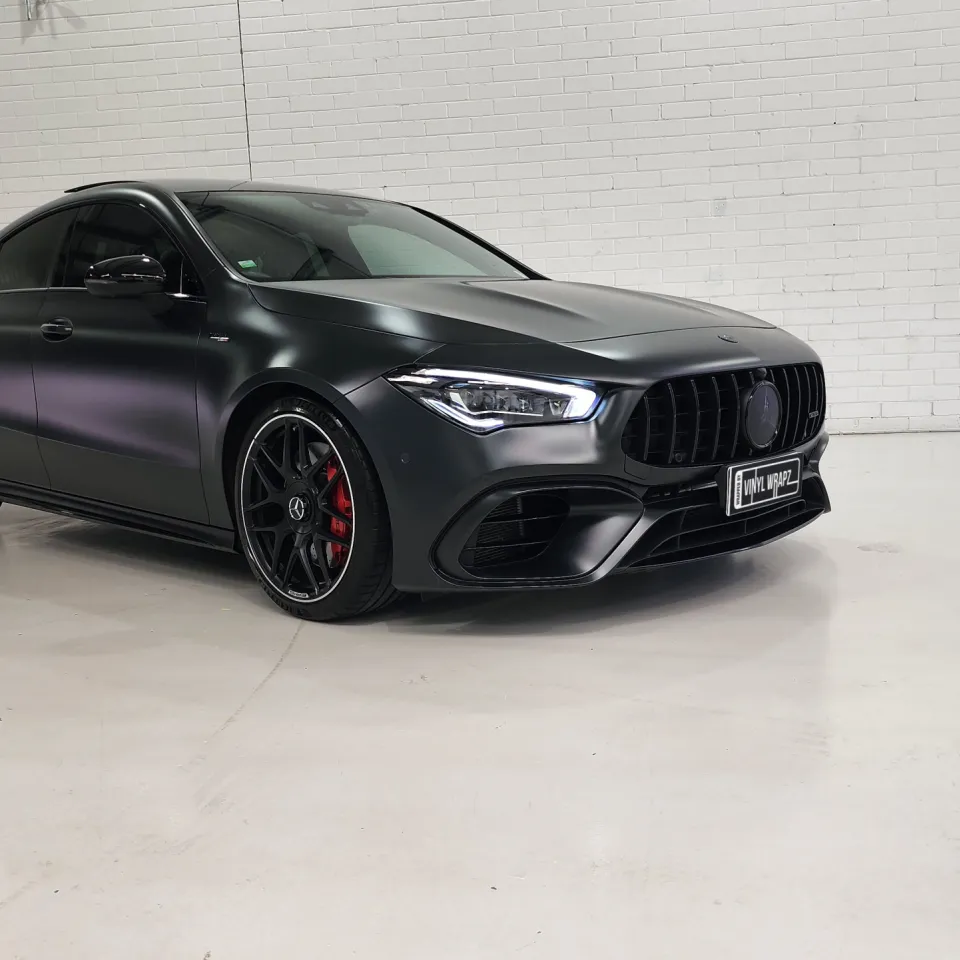 Satin dark grey Mercedes-AMG CLA 45 S against a white workshop wall