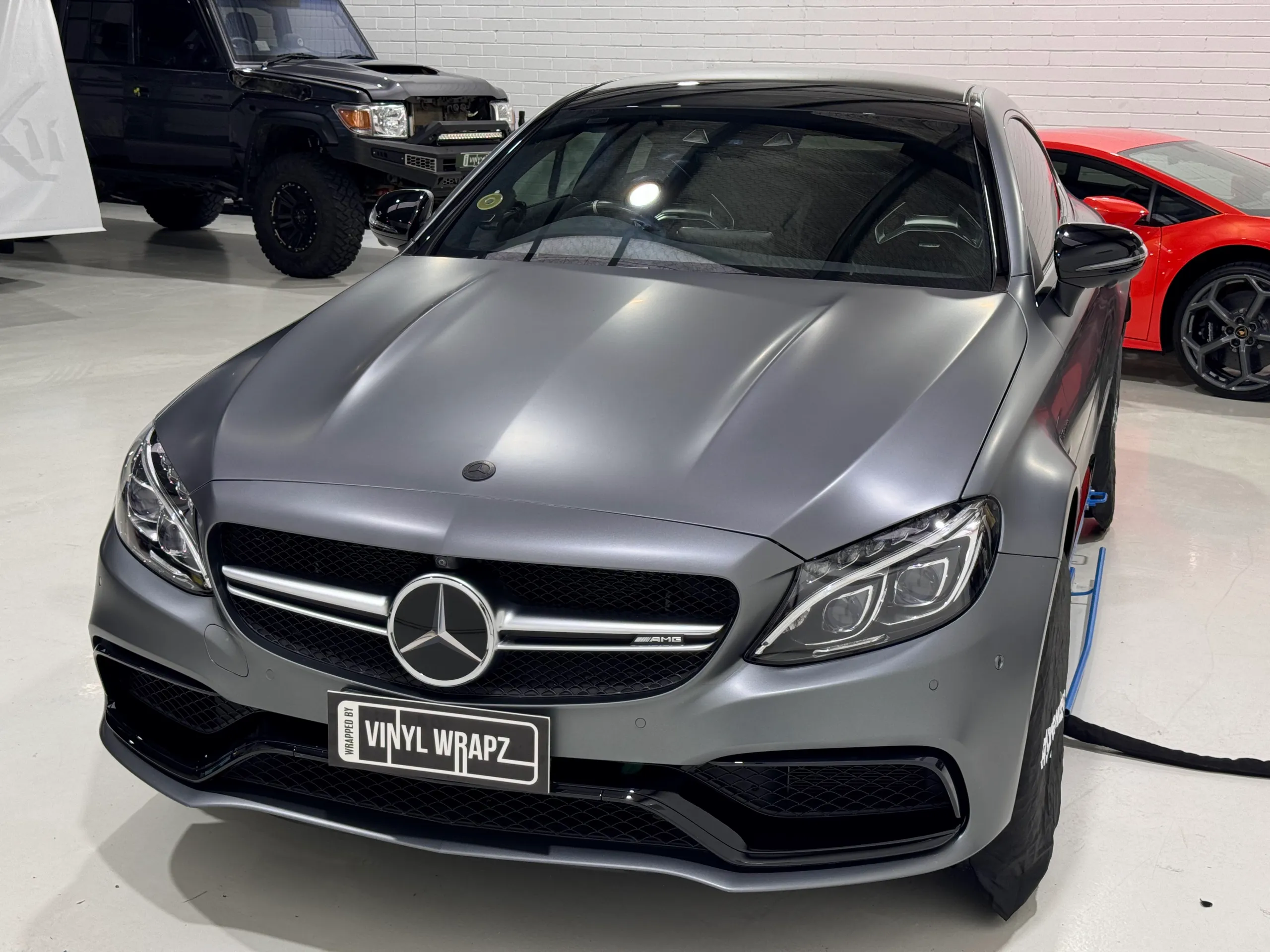 Satin grey Mercedes-AMG C63 S coupe viewed from the front quarter in the workshop