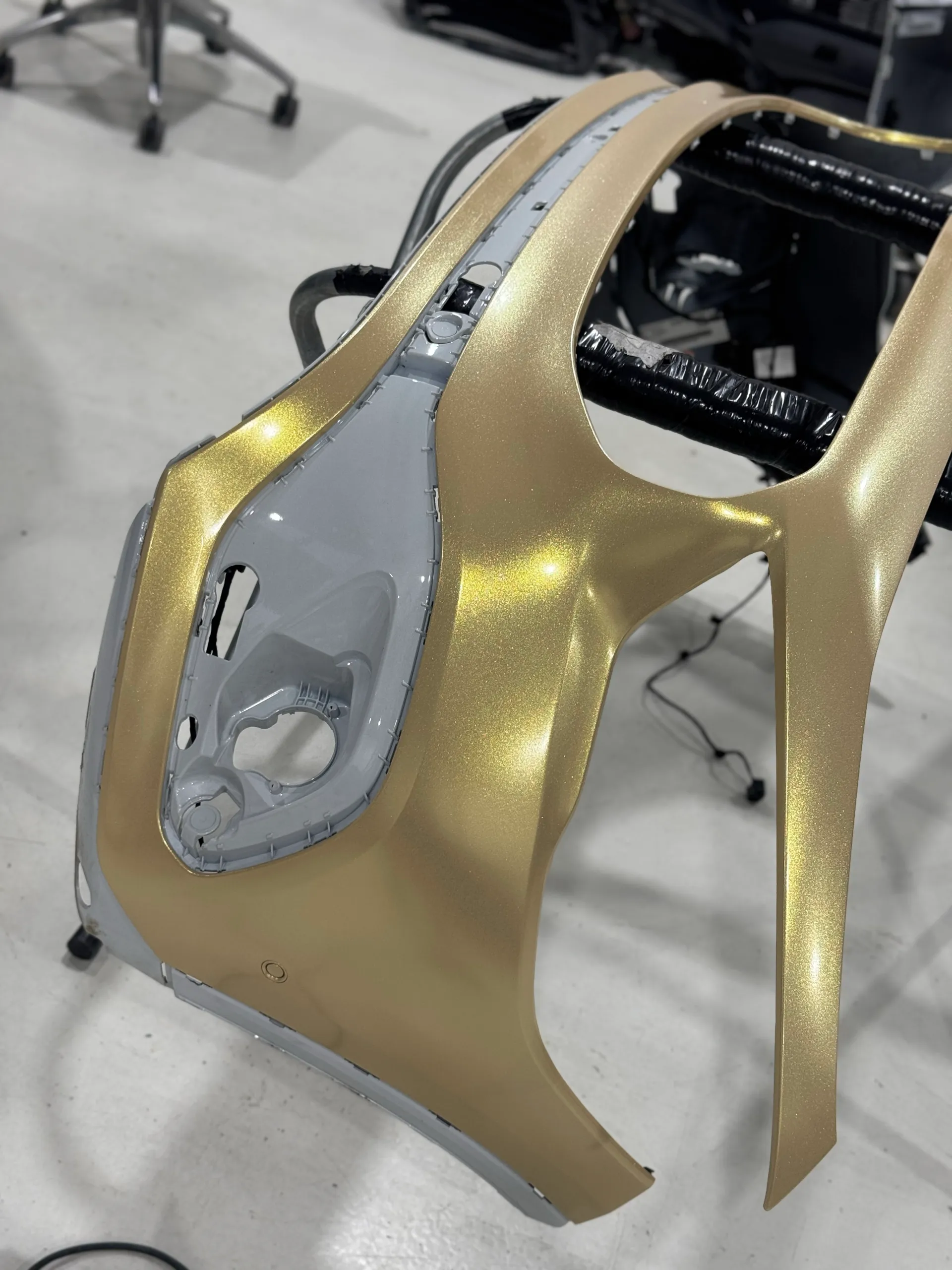 Gold shimmer film fitted around a removed Mercedes-Benz GLA front bumper on a workshop stand