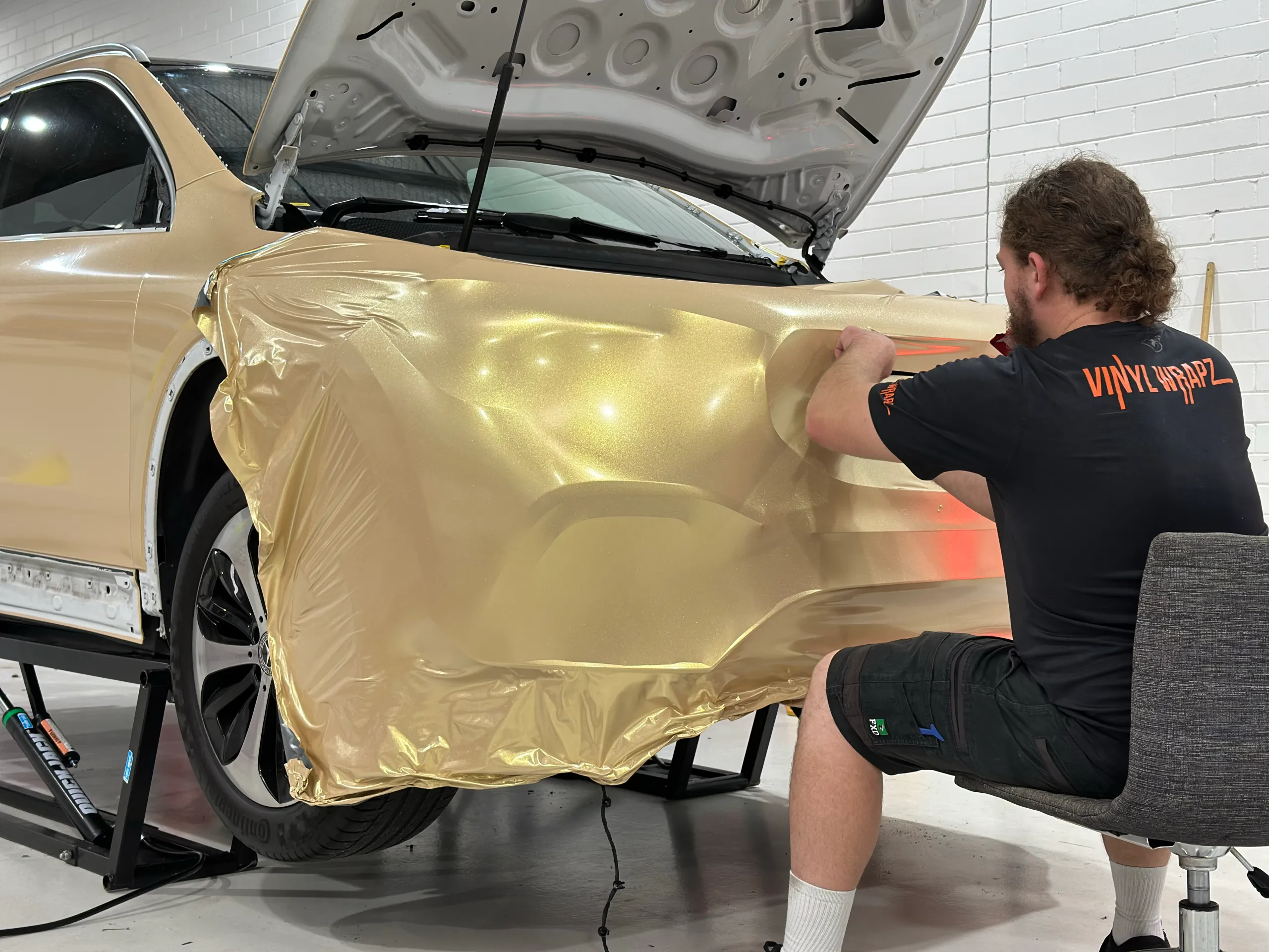 Gold shimmer film being stretched across the Mercedes-Benz GLA front bumper