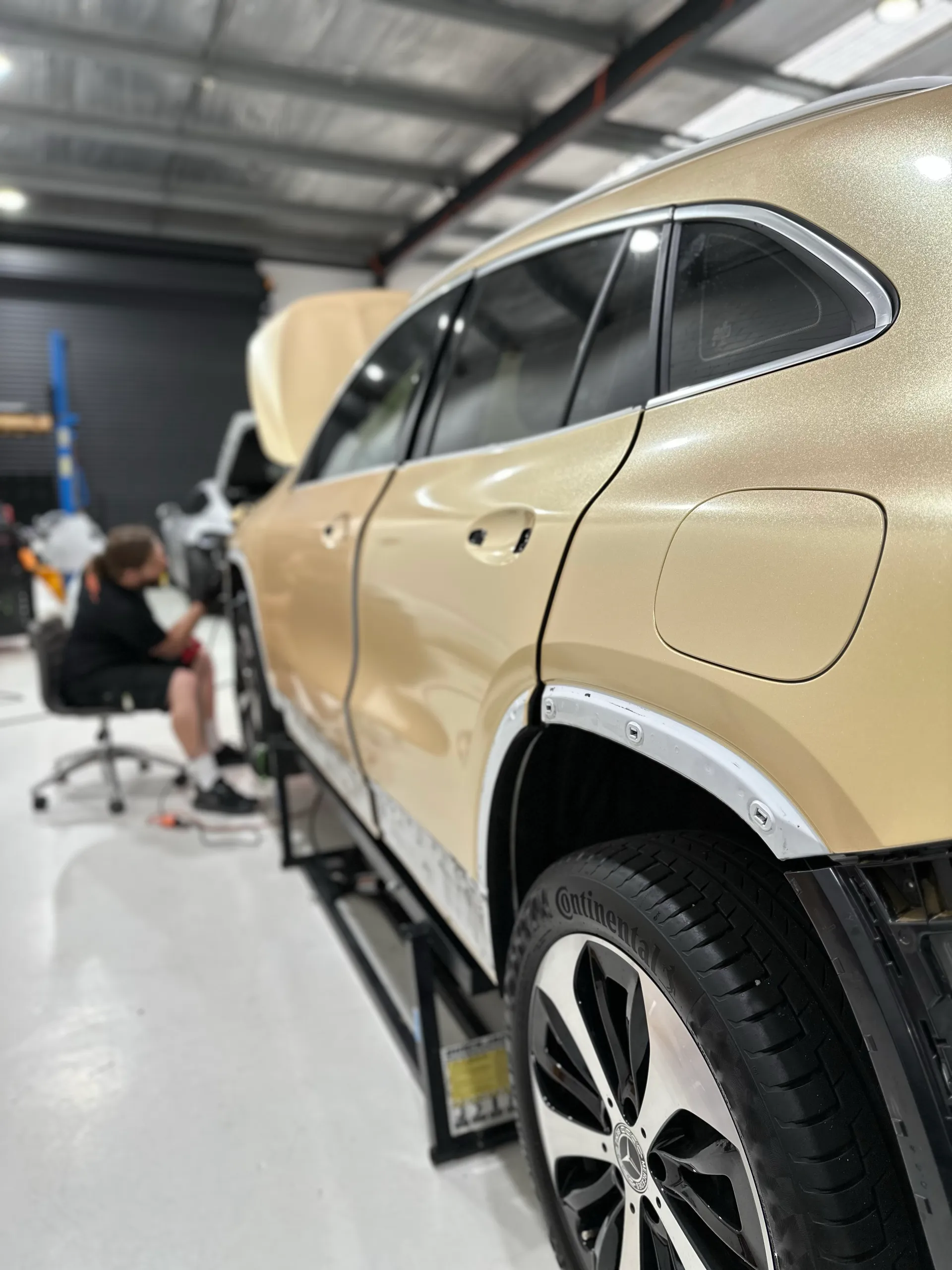 Gold Mercedes-Benz GLA side panels during wrapping with wheel-arch trim removed