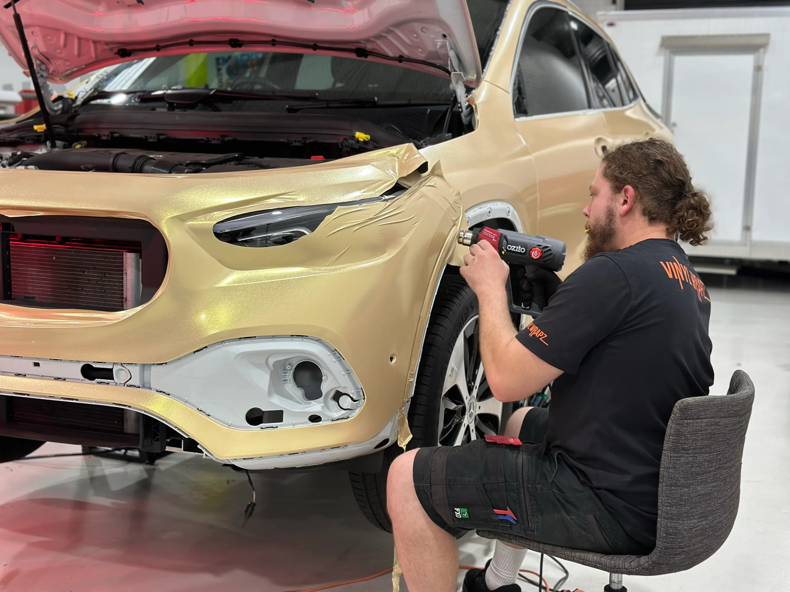 Installer heating gold shimmer film around the Mercedes-Benz GLA front bumper