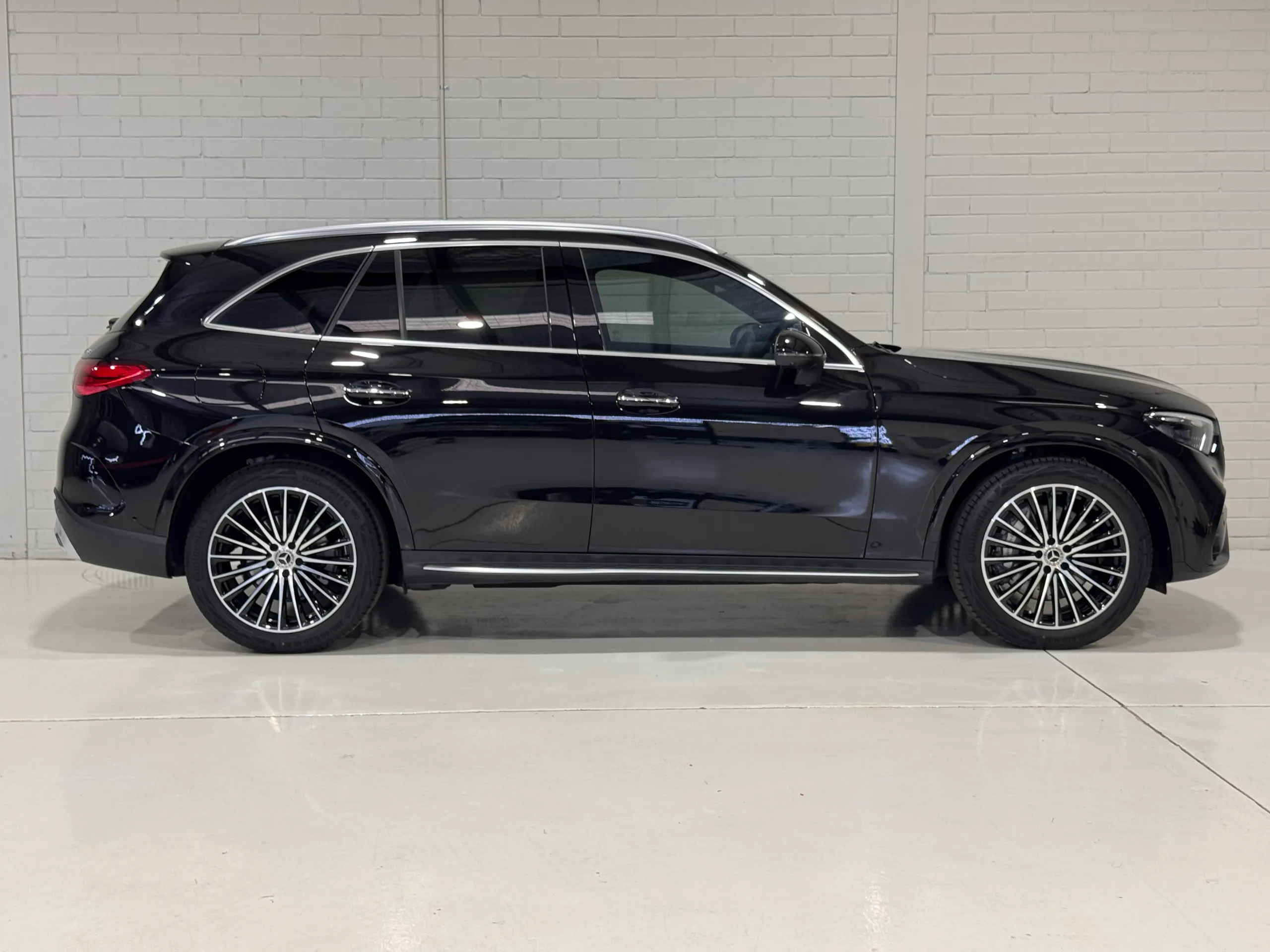 Full side profile of a gloss black Mercedes-Benz GLC 300 against a white workshop wall