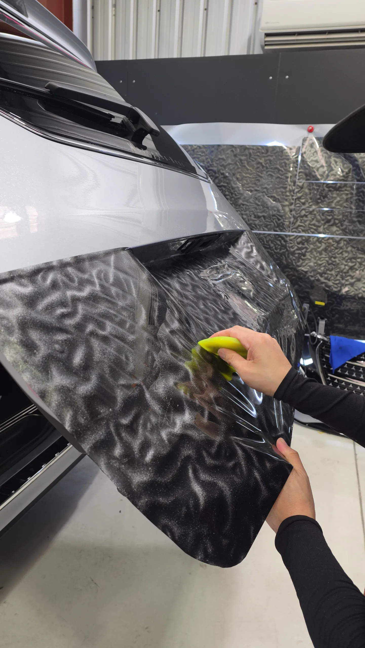 Installer's hands smoothing patterned grey film onto a Mercedes-Benz V-Class door