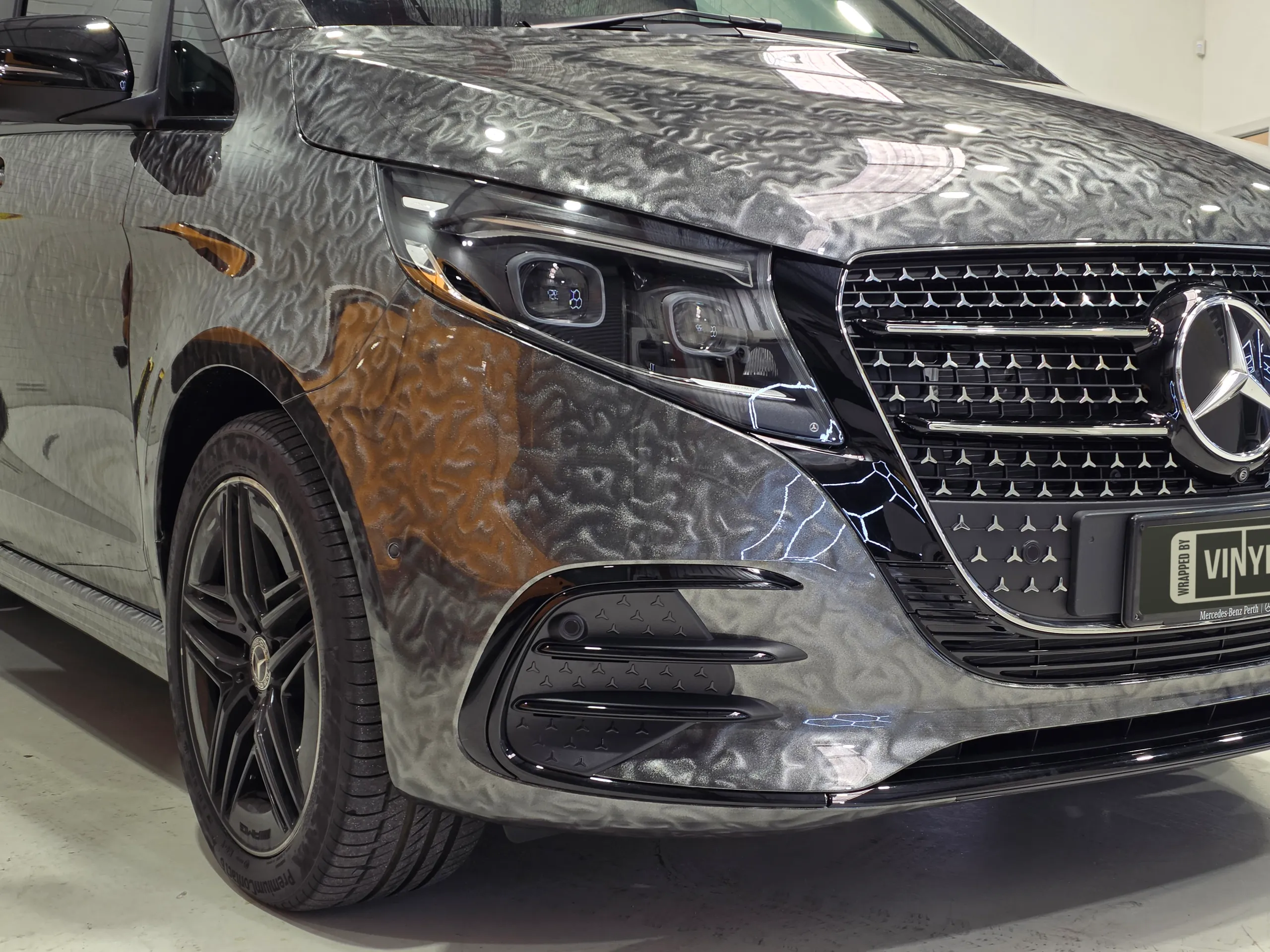 Patterned grey Mercedes-Benz V-Class front wheel, headlight and grille in the workshop