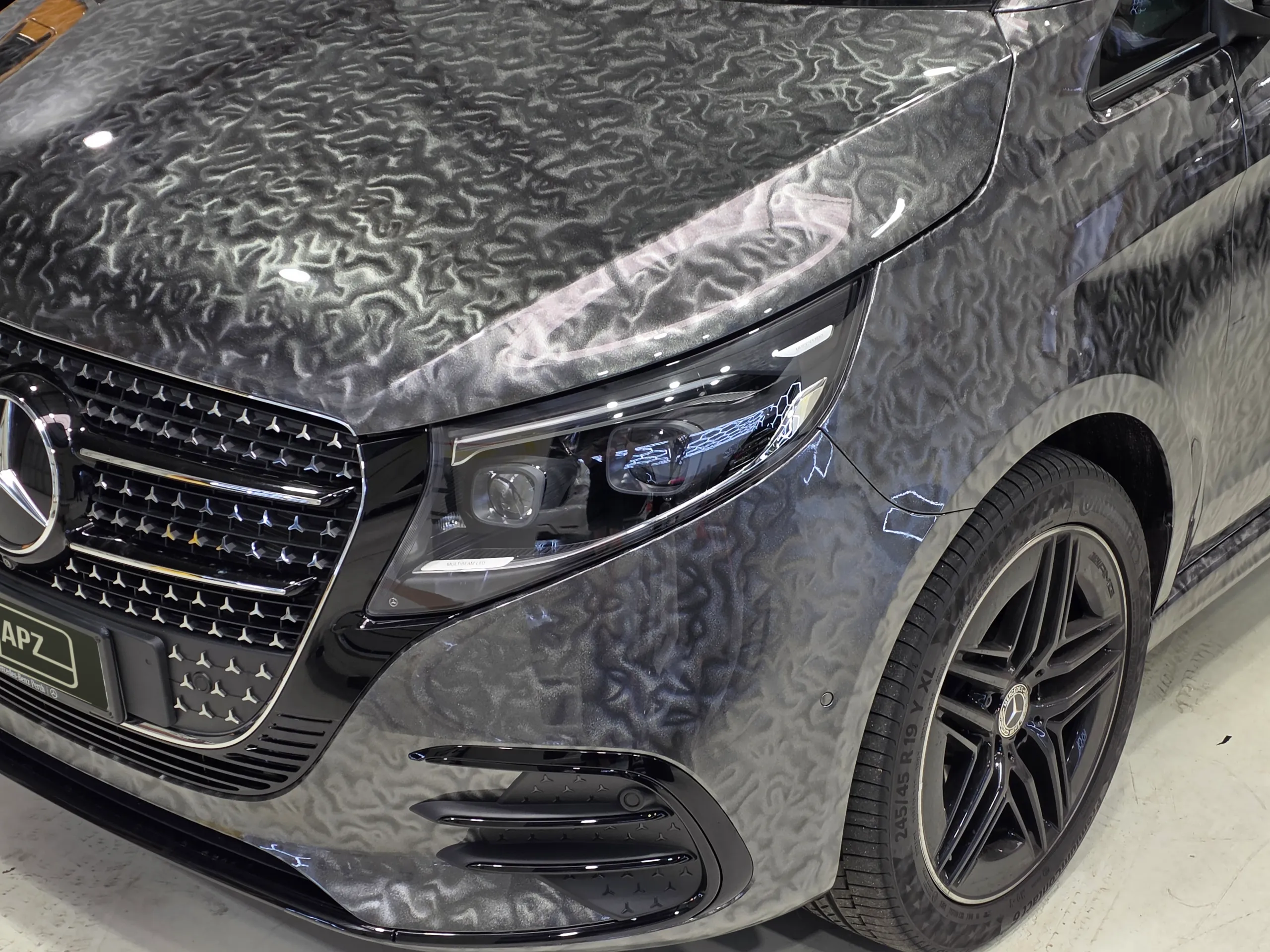Mercedes-Benz V-Class front corner with patterned grey film and a black alloy wheel
