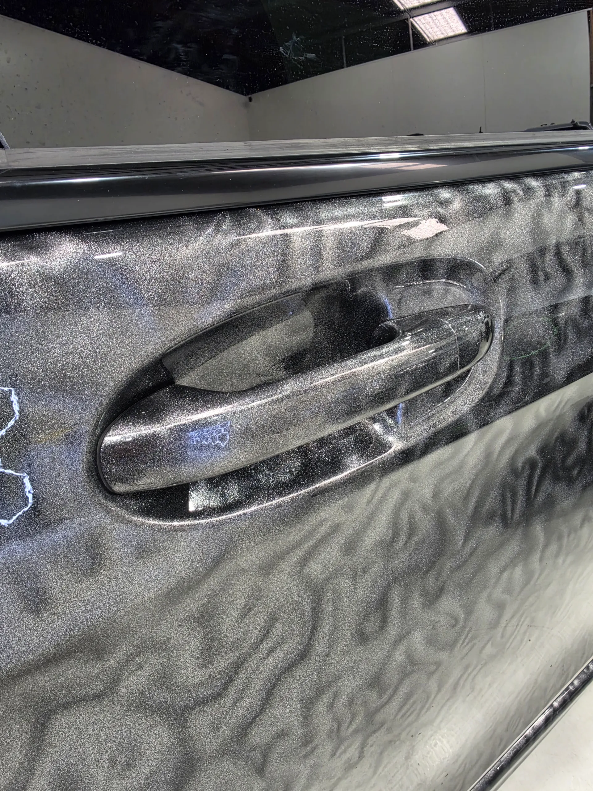 Close-up of the Mercedes-Benz V-Class door handle and surrounding patterned grey film