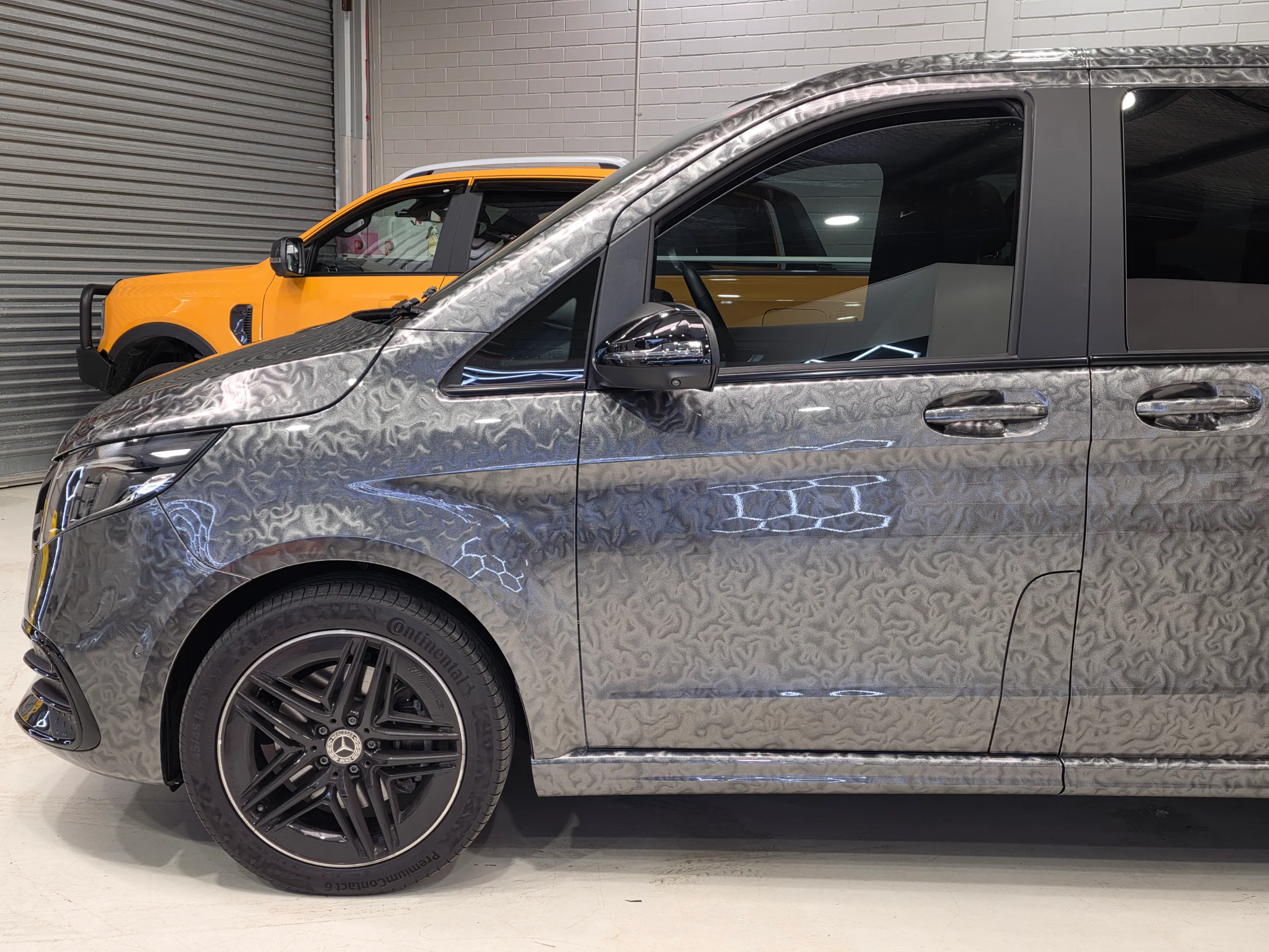 Patterned grey Mercedes-Benz V-Class front wheel, cab and door in the workshop