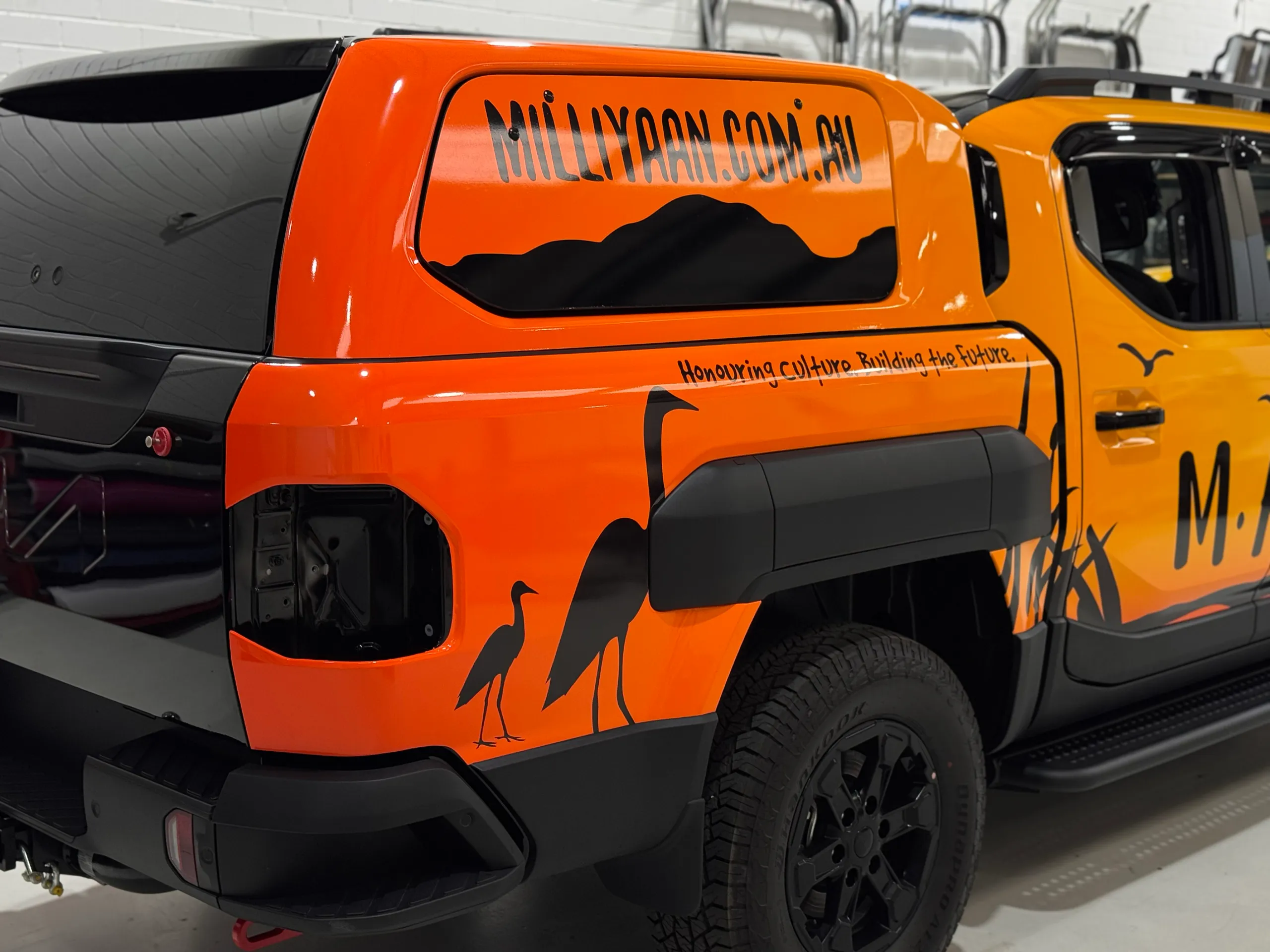 Orange Kia Tasman canopy and rear quarter during wrapping with the rear light removed