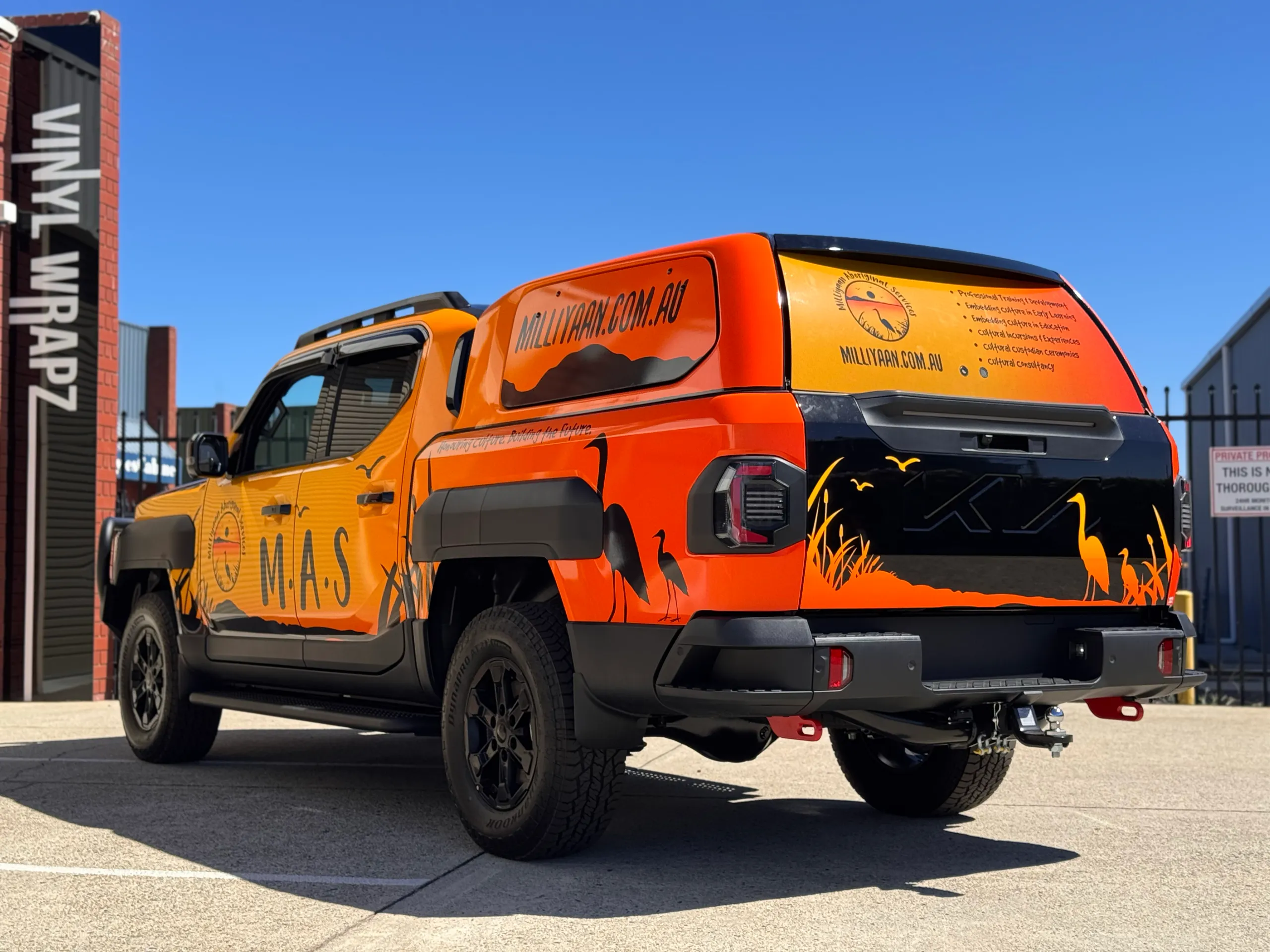Milliyaan Kia Tasman with orange canopy graphics and black bird silhouettes outdoors