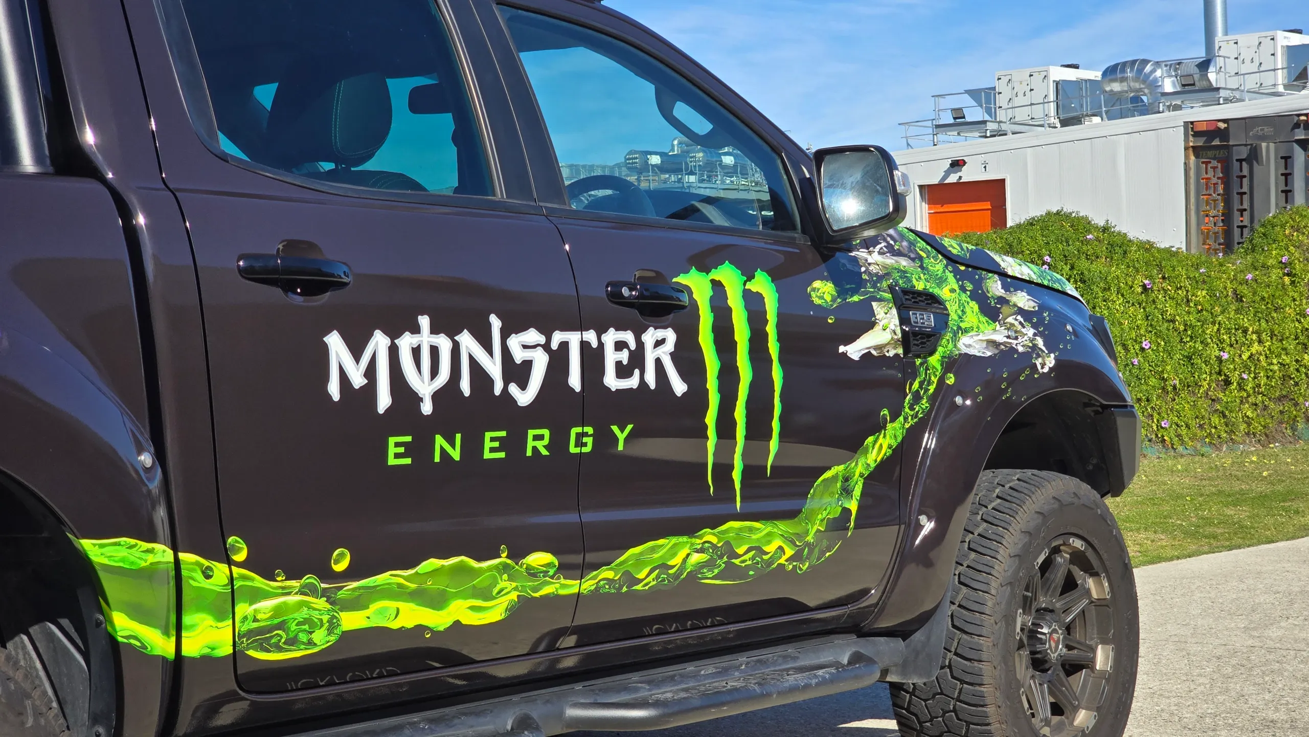 Monster Energy logo and green splash graphics across the dark grey Ford Ranger doors
