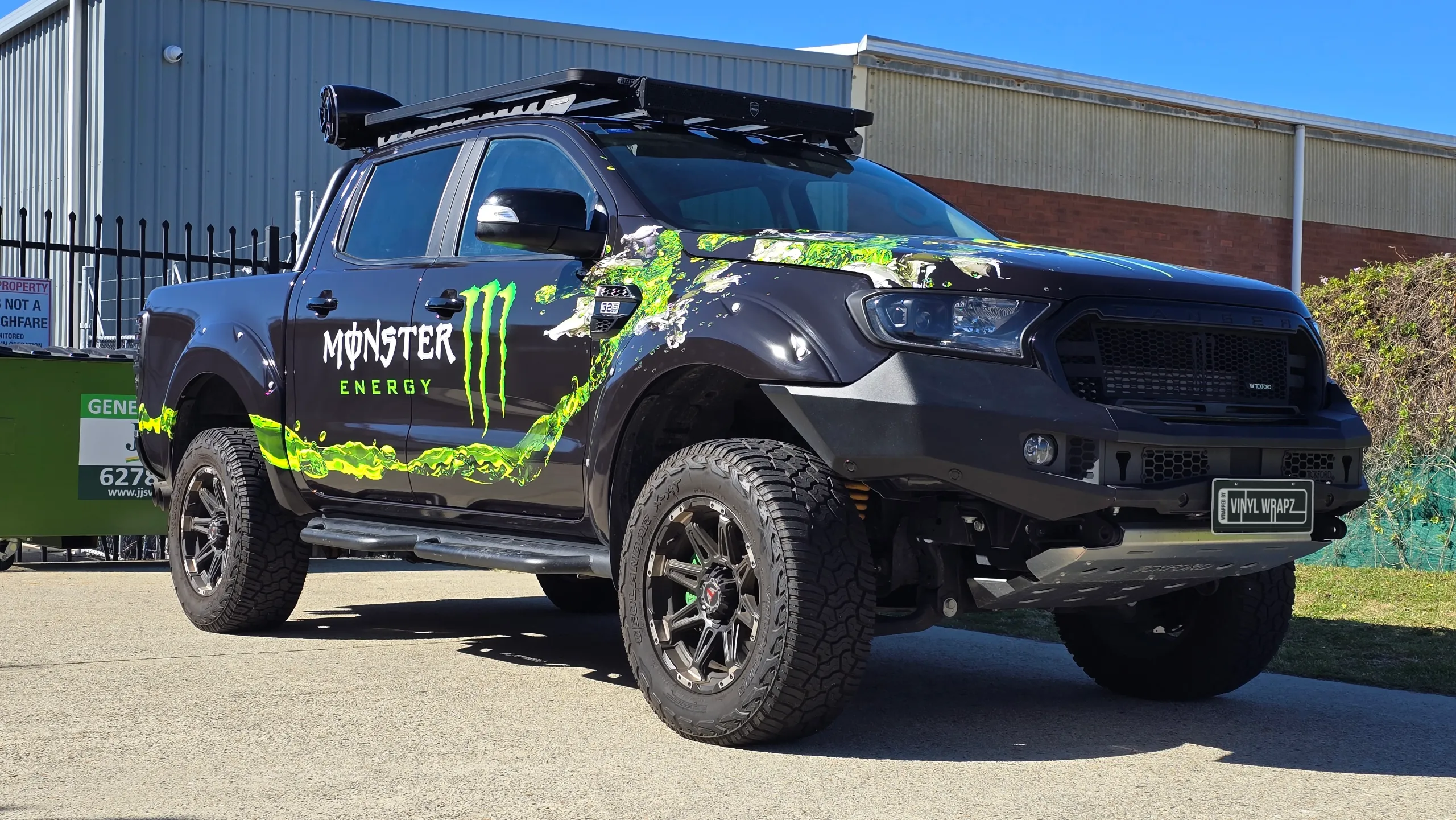 Ford Ranger with green Monster Energy graphics, off-road wheels and a roof rack outdoors