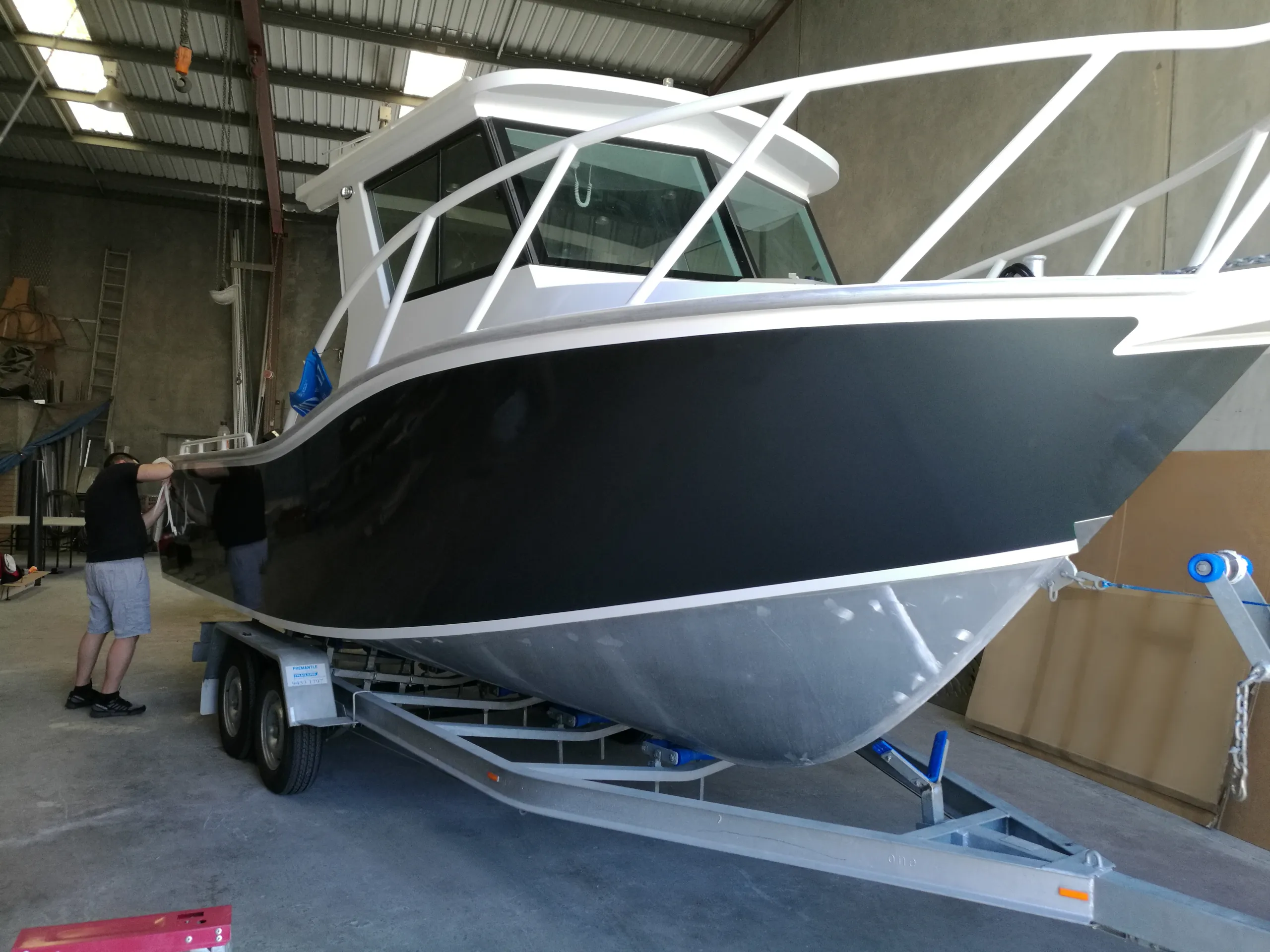 Installer working along the charcoal boat hull while it rests on its trailer