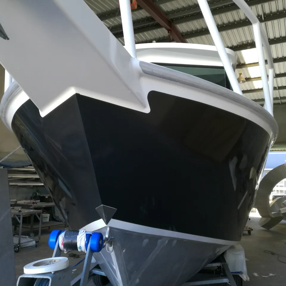 Charcoal boat bow beneath white rails and a white cabin in the workshop