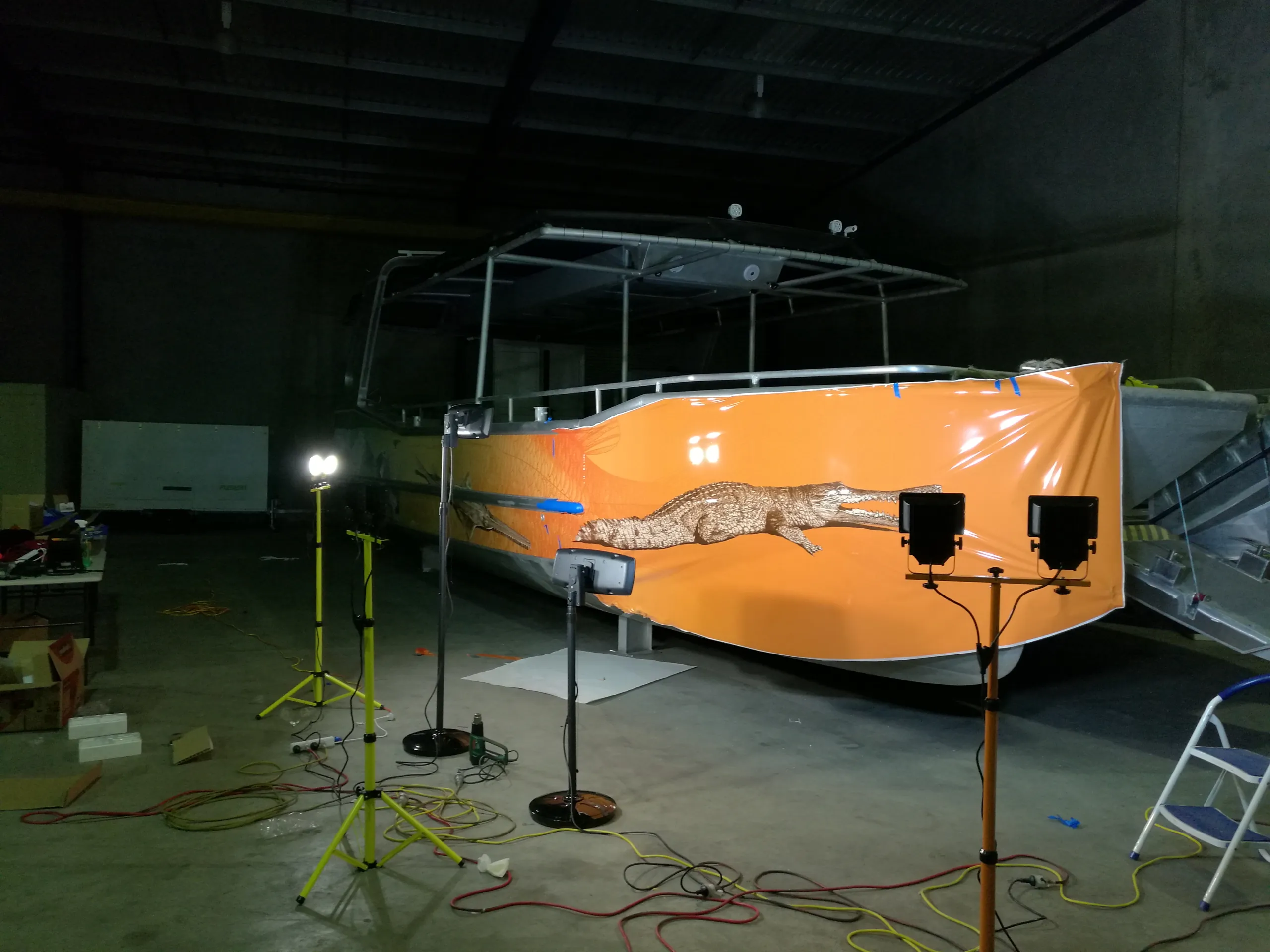 Orange crocodile wrap film around a boat bow, with loose edges during installation