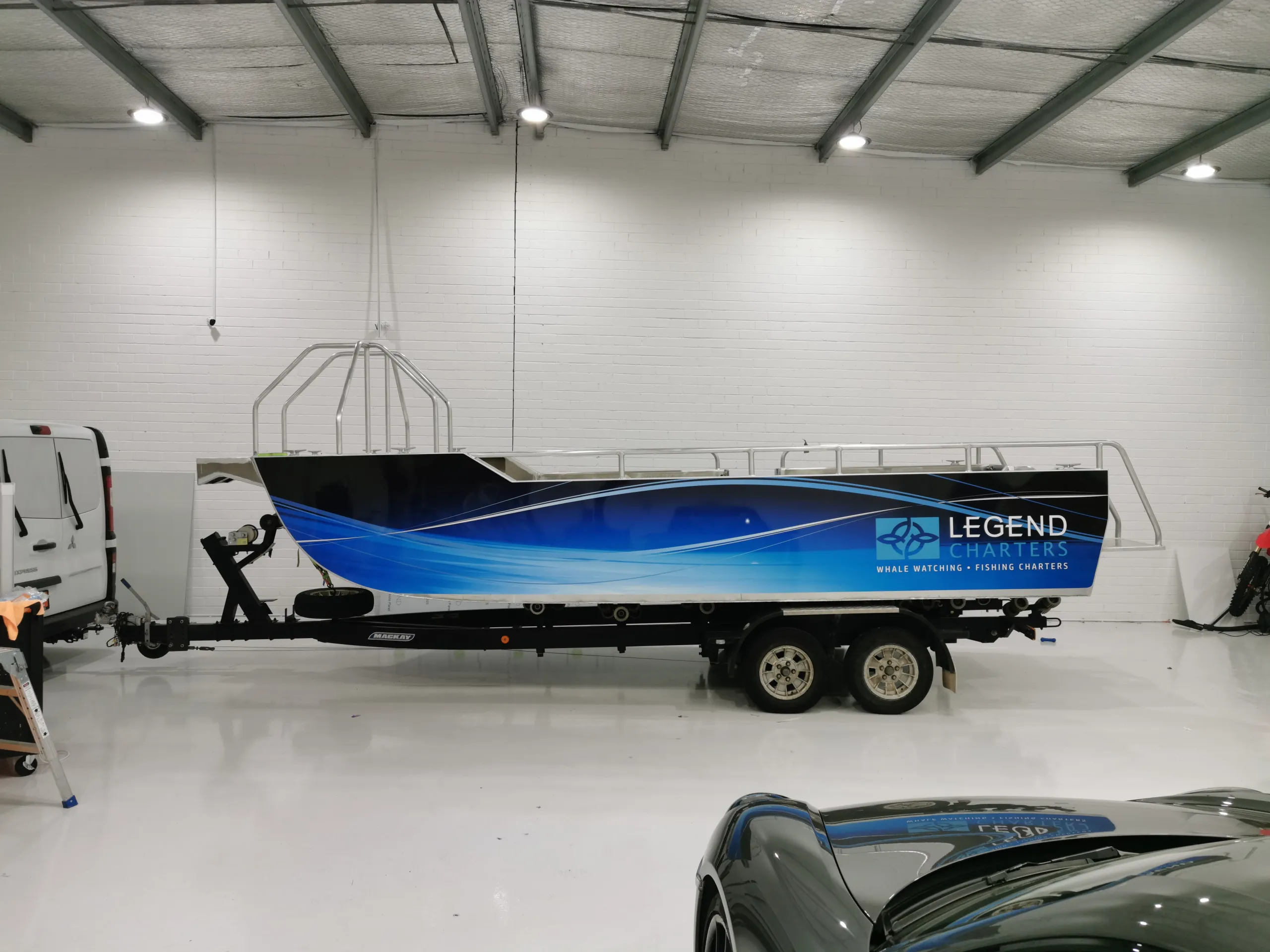 Small Legend Charters boat with blue hull graphics on a trailer in the workshop