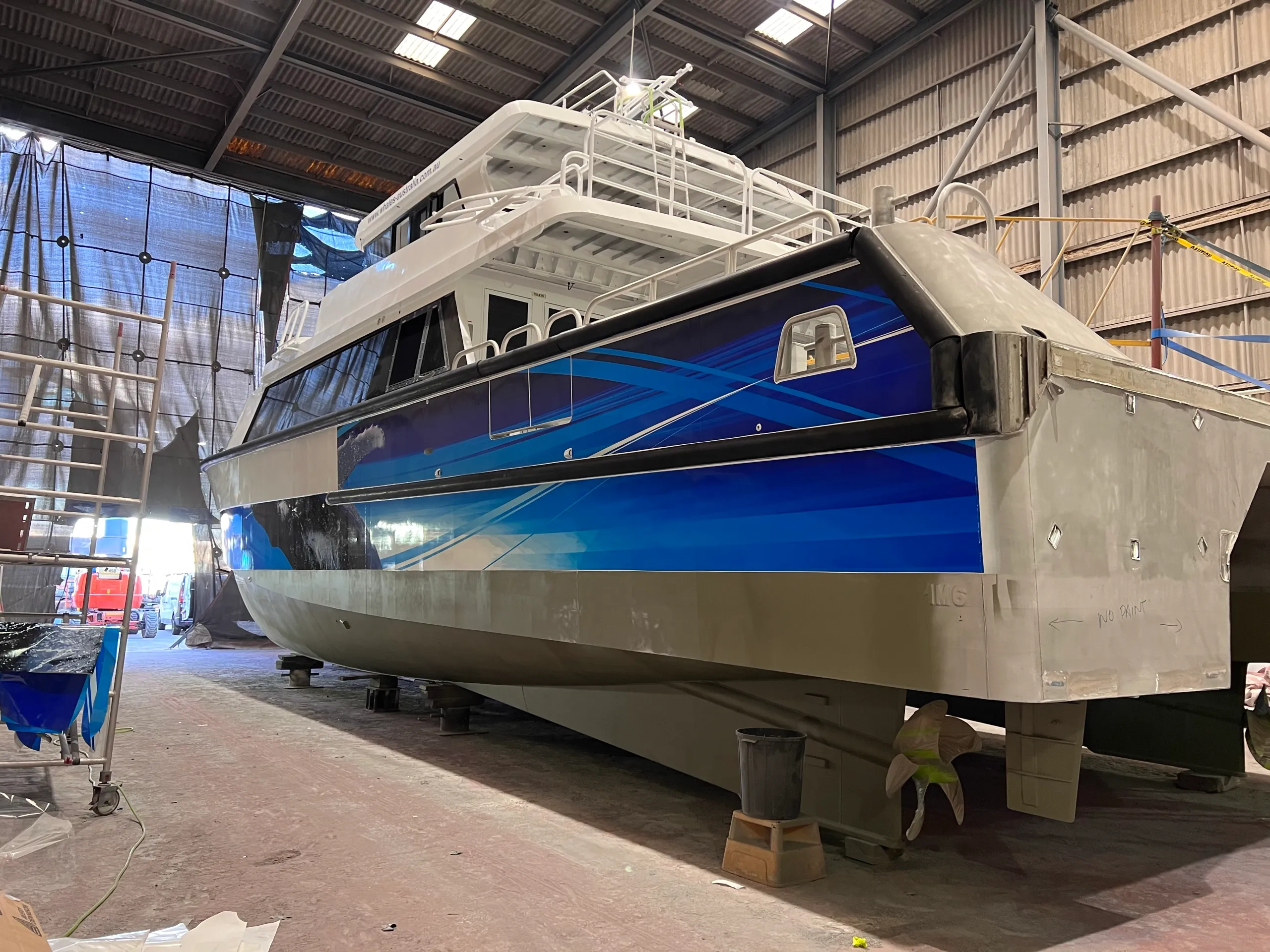 Blue graphics on the Naturaliste Charters catamaran stern quarter during its refit