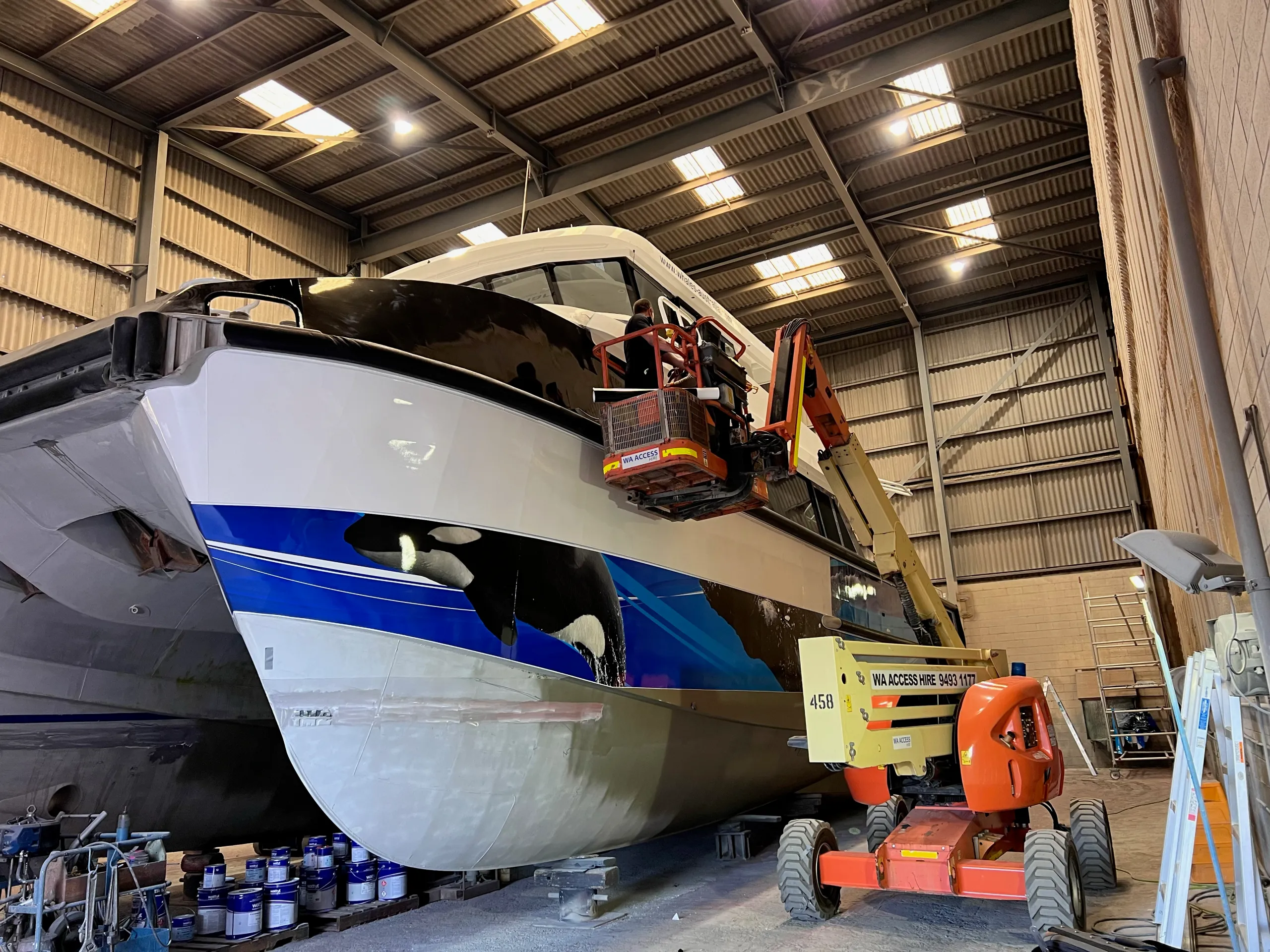 Installers working above the Naturaliste Charters catamaran bow from a boom lift