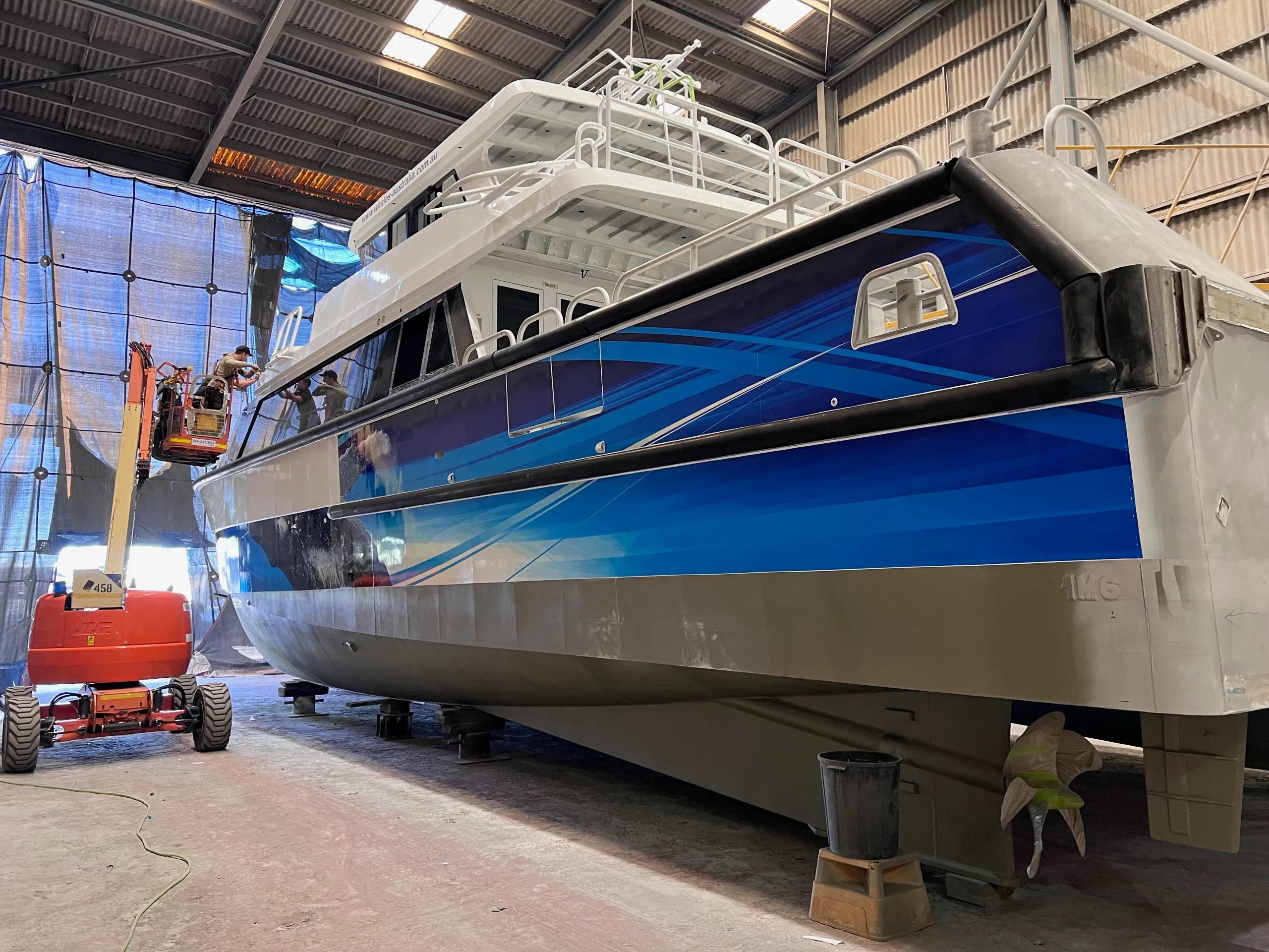 Naturaliste Charters catamaran stern quarter during graphics installation from a boom lift
