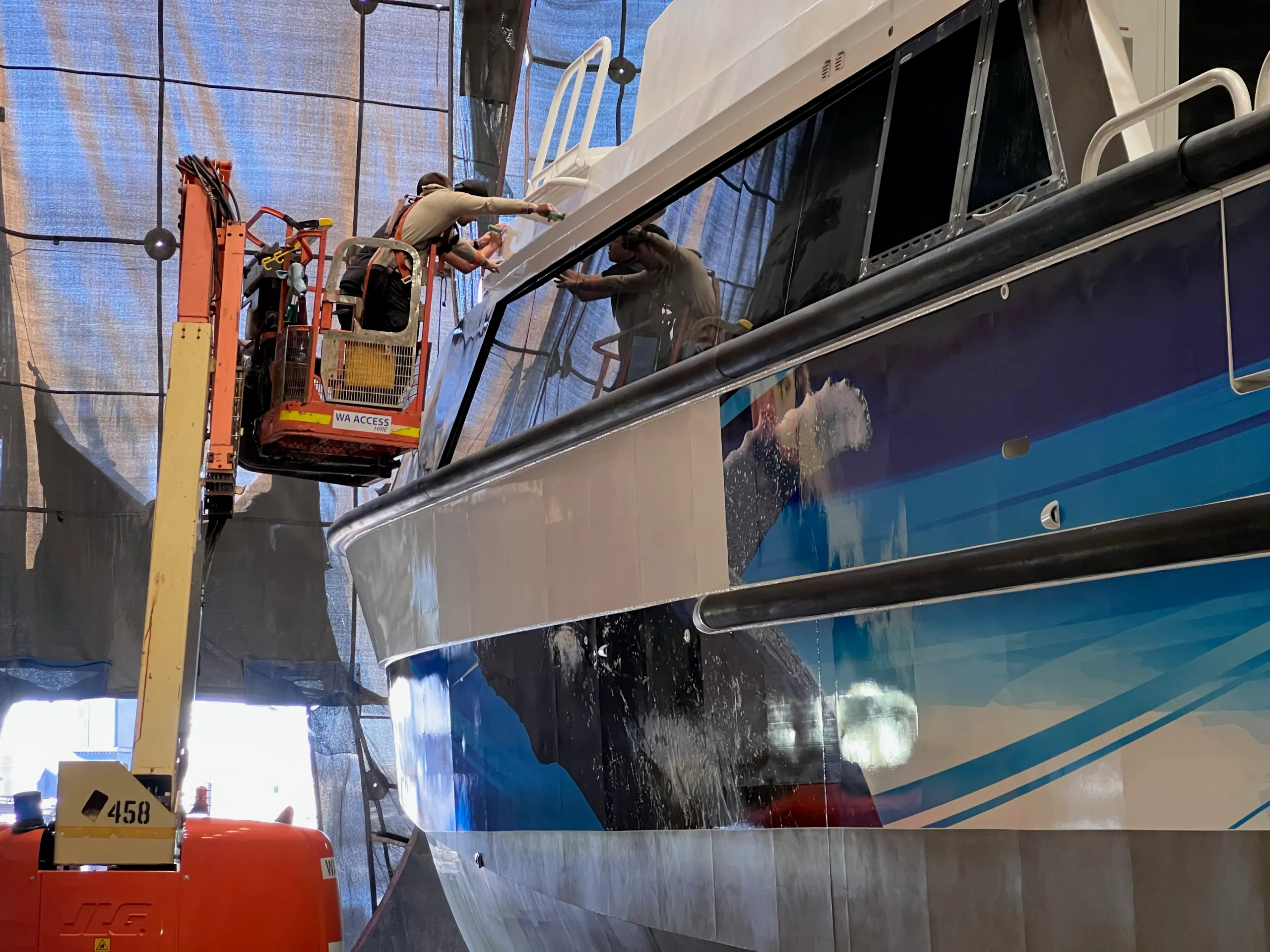 Installer working beside the Naturaliste Charters catamaran windows from a raised boom lift