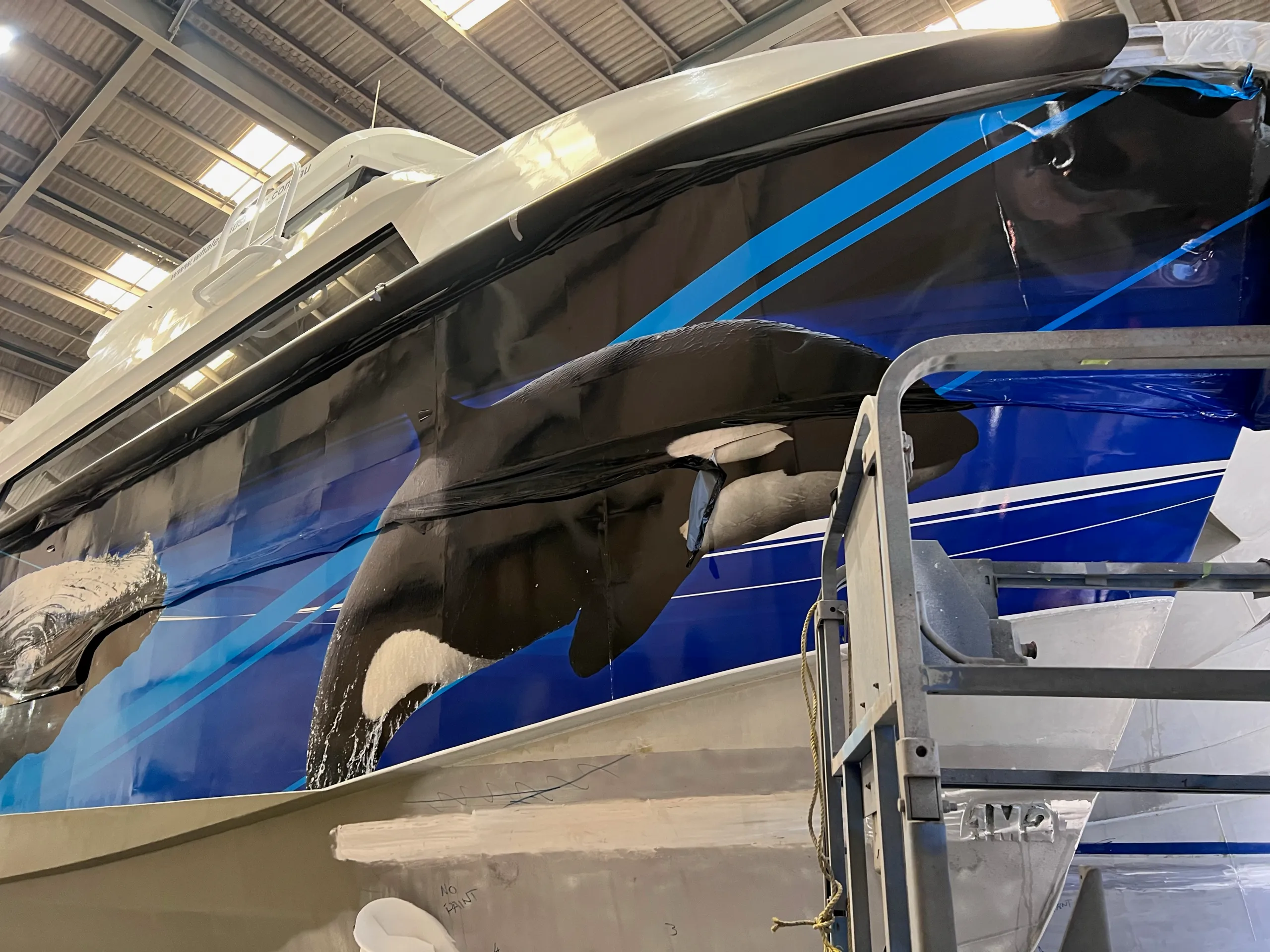 Partly fitted orca graphics on the Naturaliste Charters catamaran bow beside a work platform