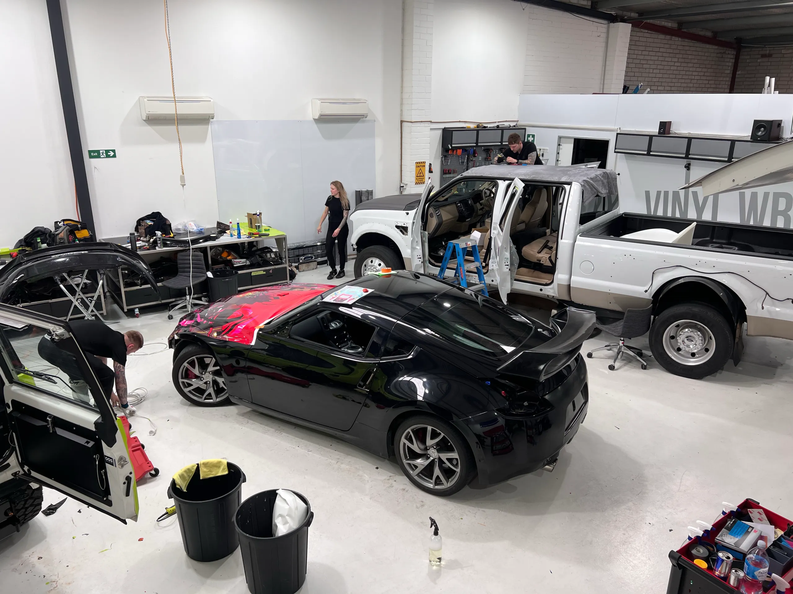 Elevated workshop view of the Nissan 370Z during preparation, with installers nearby
