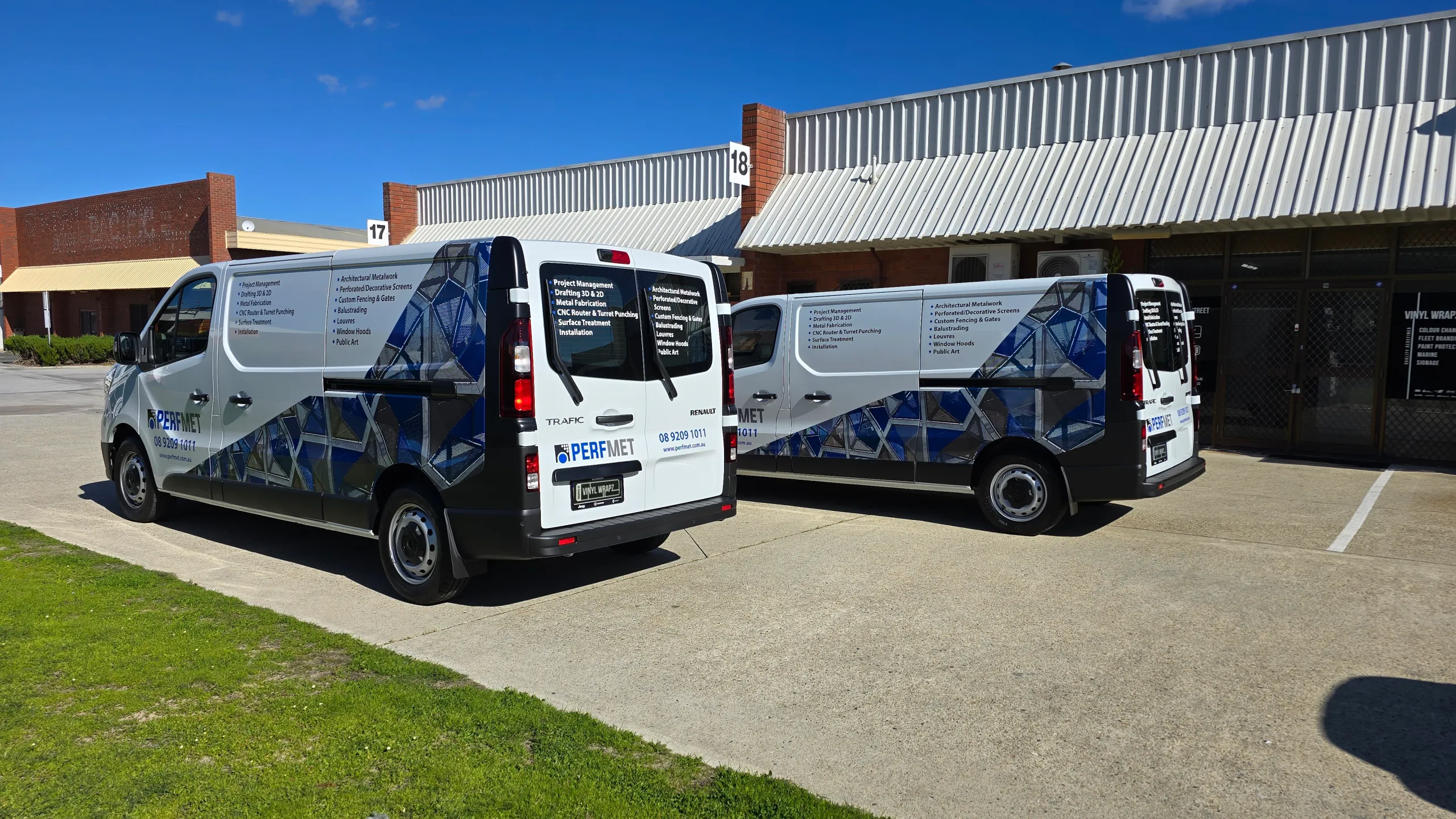 Rear-quarter view of two Perfmet Renault Trafic vans with blue geometric graphics