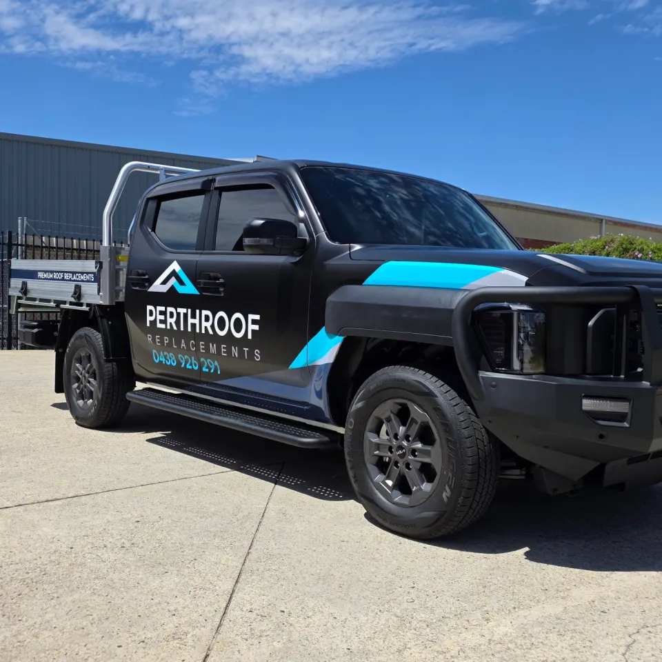 Satin black Kia Tasman tray ute with cyan and grey PerthRoof Replacements graphics