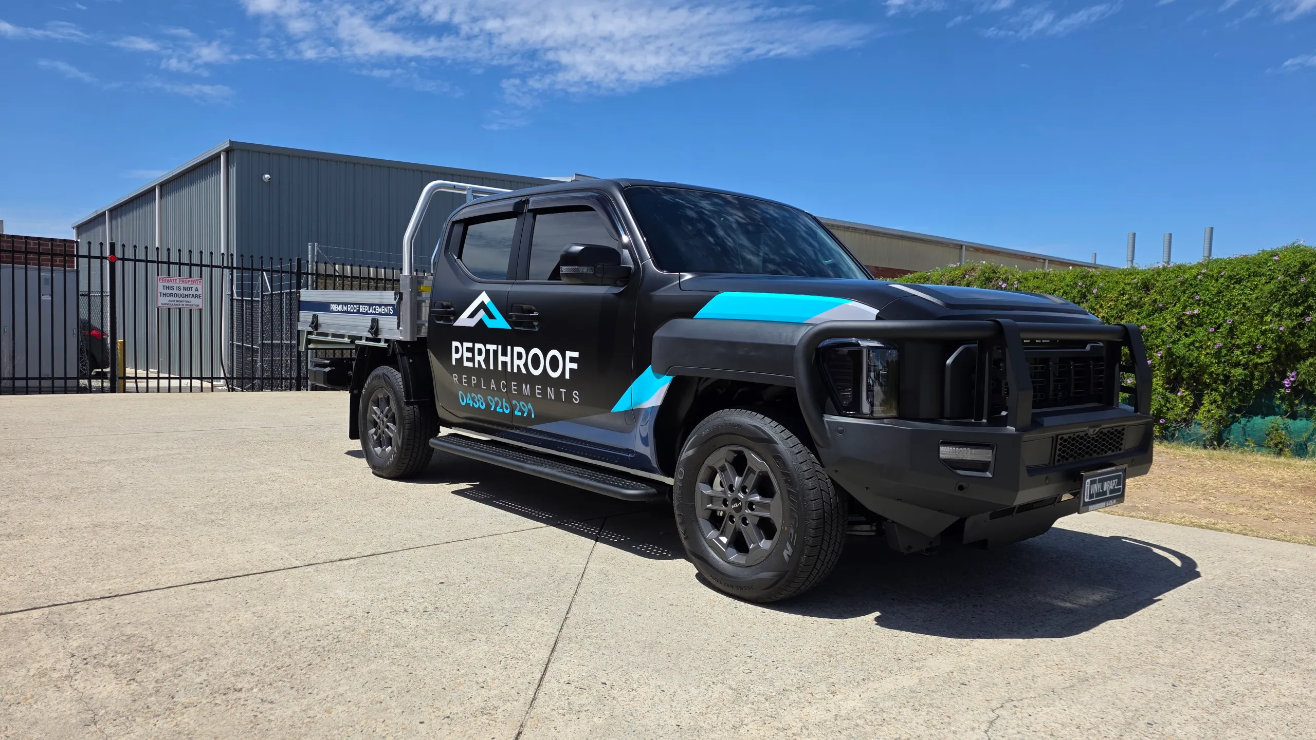 Satin black Kia Tasman tray ute with cyan and grey PerthRoof Replacements graphics
